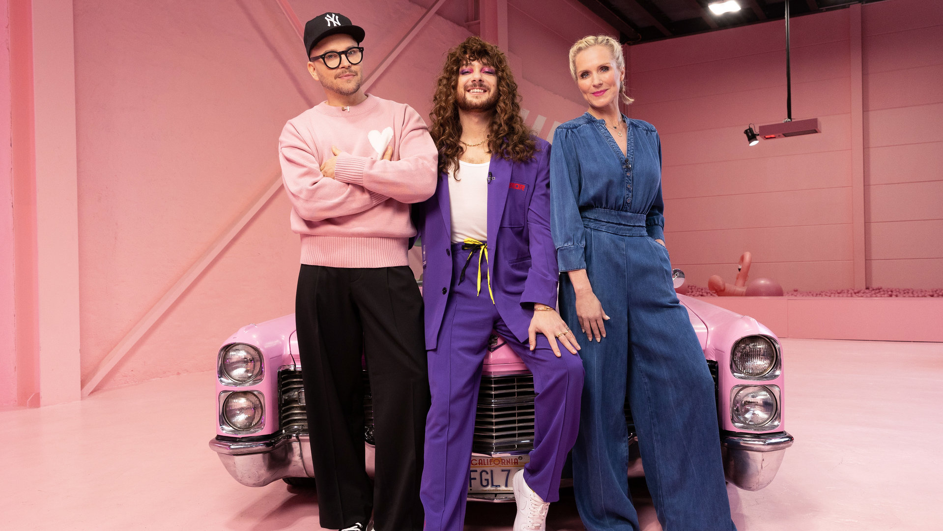 "Glow Up - Deutschlands nächster Make-up-Star: Social Media": Armin Morbach, Riccardo Simonetti und Loni Baur posieren vor einem pinken Cadillac. Sie schauen direkt in die Kamera.