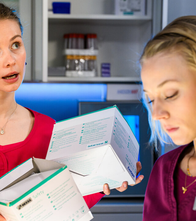 "Bettys Diagnose - Halbe Wahrheiten": Frida (Johanna Hens) steht neben Mia (Antonia Döring) und hält dabei zwei kleine Kartons in den Händen.