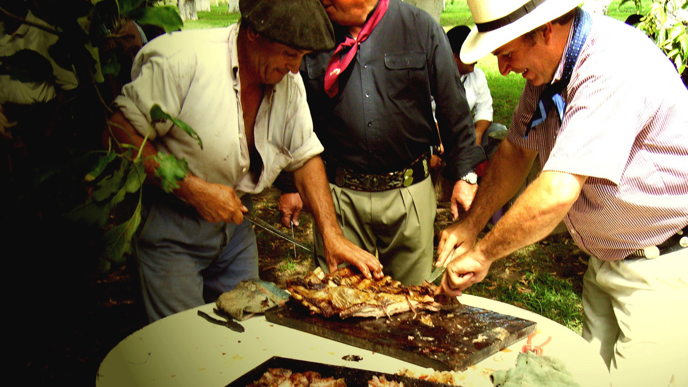 Daniel Pérez (li.) schneidet das "Carne al Asador", das auf offenem Feuer gegrillte Fleisch, zu.
