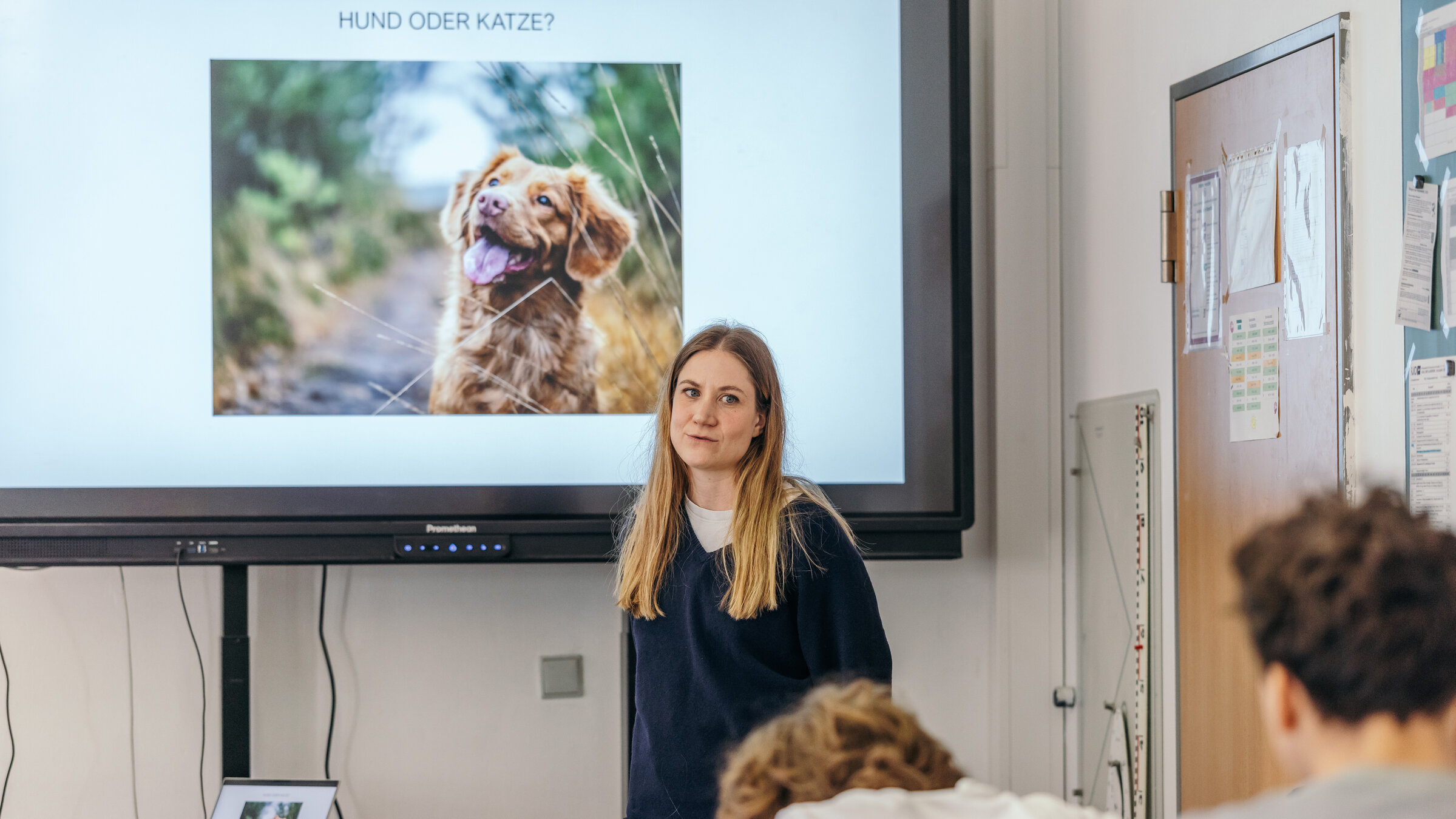 "37°Leben: Life Teacher: Was nicht im Lehrplan steht": Charlotte steht vor einer Gruppe Schülern im Klassenraum. Auf dem Screen hinter ihr ist ein Hund abgebildet.