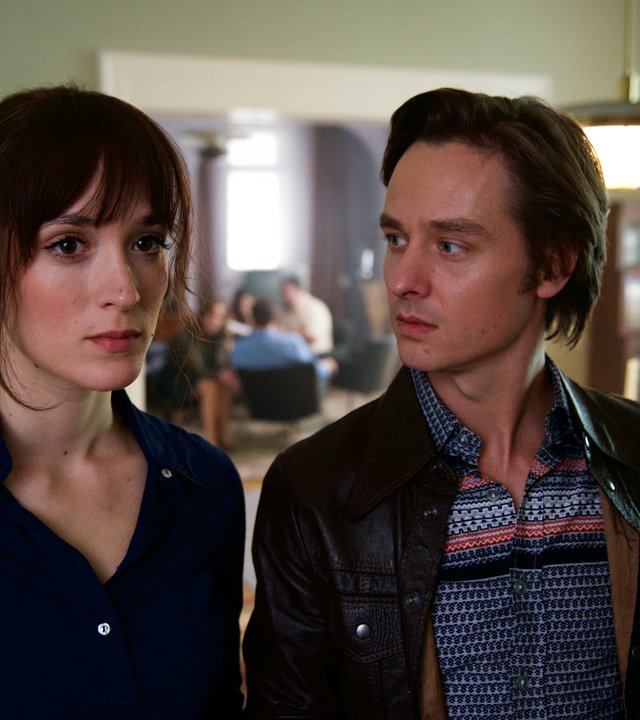 "Der gleiche Himmel (3)": Sabine Cutter (Friederike Becht) und Lars Weber (Tom Schilling) stehen Schulter an Schulter im Esszimmer der Familie Cutter. Lars schaut Sabine an. Im Hintergrund ist der Rest der Familie zu sehen.