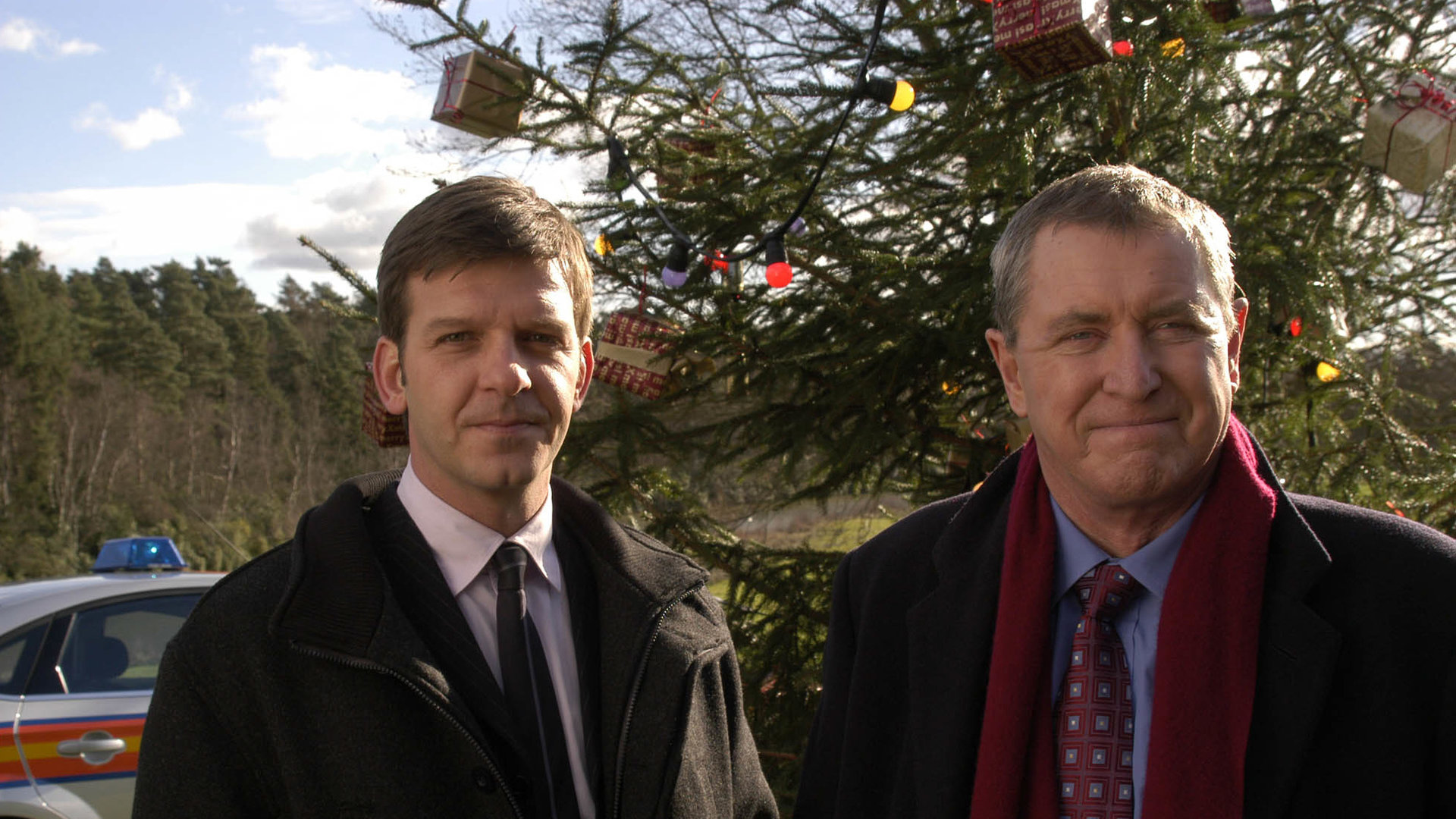 "Inspector Barnaby - Ein missratener Sohn": DS Ben Jones (Jason Hughes) und DCI Tom Barnaby (John Nettles) kommen am Tatort an. Im Hintergrund ist ein großer geschmückter Tannenbaum zu sehen.