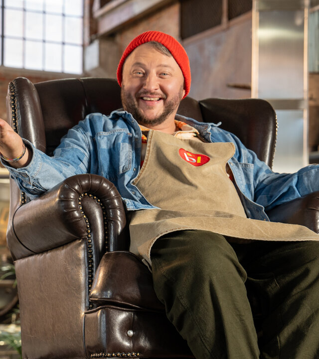 "besseresser: Die Tricks von Ikea - Kötbullar, Hot Dog & Co. - Sebastian Lege deckt auf": Sebastian sitzt in einem braunen Sessel in seiner Werkstatt.