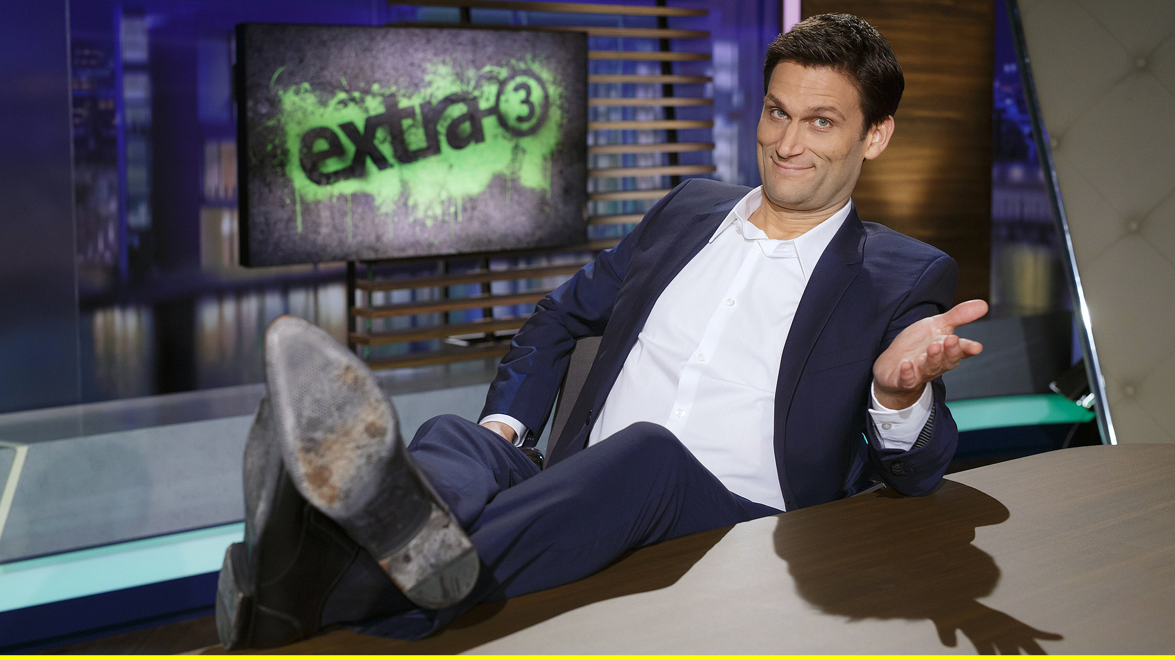 "extra 3": Moderator Christian Ehring im Studio mit hochgelegten Beinen.
