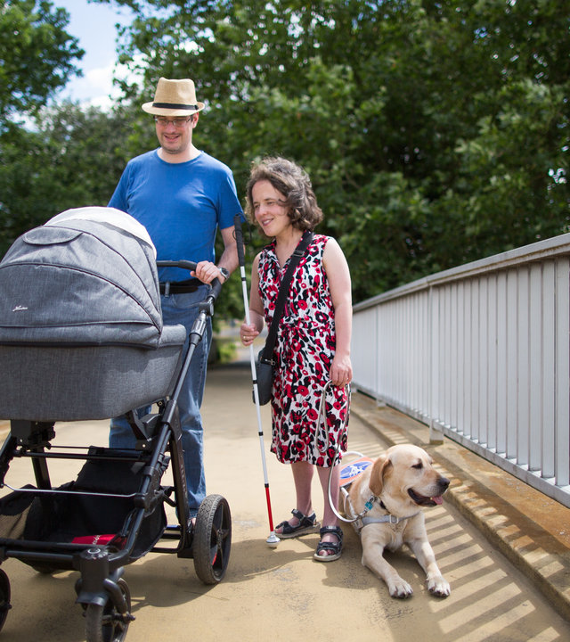 "einfach Mensch - Ulrike und Christian Karges: Wir wünschen uns ein Kind": Ulrike und Christian Karges gehen mit Kinderwagen und Hund über eine Brücke.