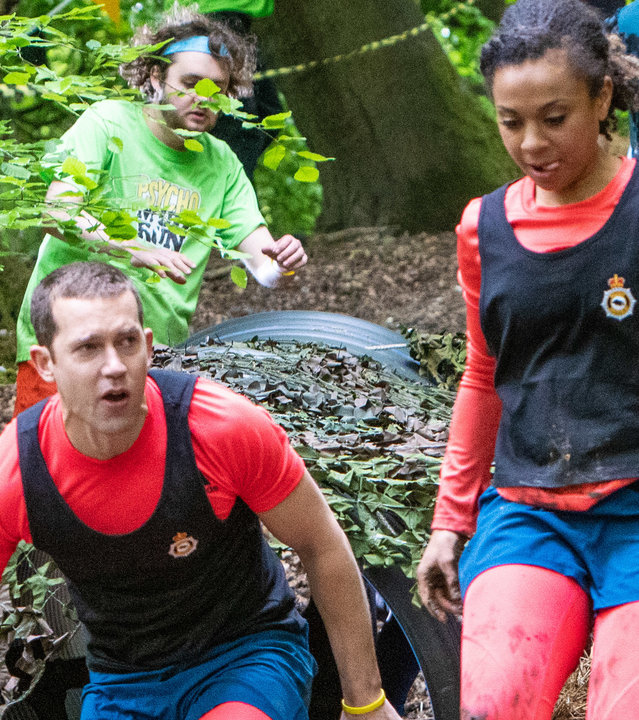 "Inspector Barnaby - Leichzeit am See": Detective Sergeant Jamie Winter (Nick Hendrix) und Police Constable Jade-Marie Pierce (Eleanor Fanyinka) beim Mud Run. Sie kommen gerade aus zwei nebeneinander liegenden Rohren, vor ihnen liegen zahlreiche Autoreifen, über die sie springen müssen.