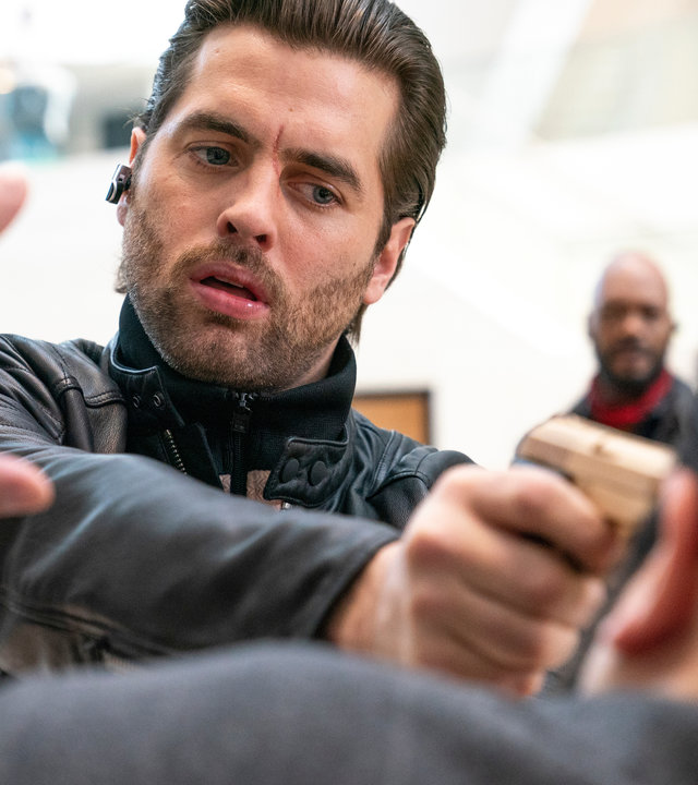 "The Bank Hacker": Prince (Manuel Broekman) hält seinem Gegenüber, der eine Hand nach oben hält, eine Pistole an den Kopf. Prince hat einen entschlossenen Gesichtsausdruck.