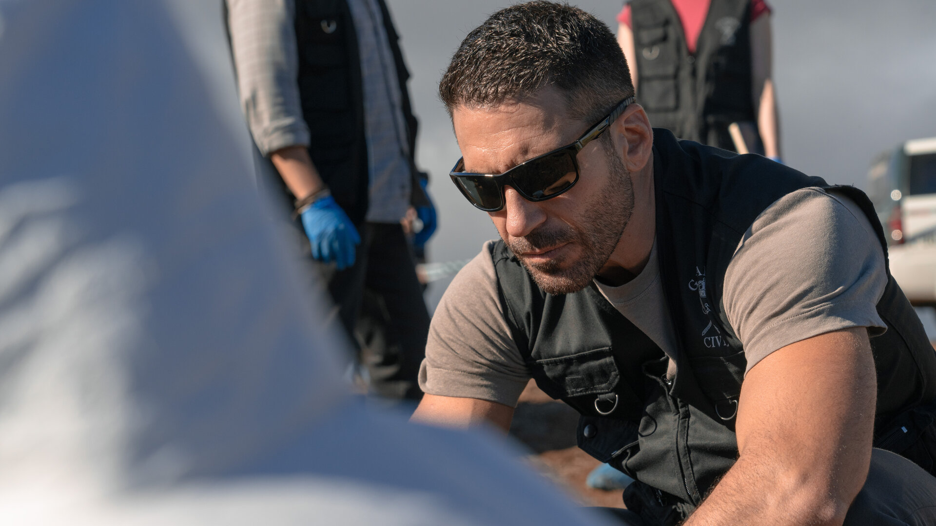 "Weiss & Morales: Eine Frage des Vertrauens": Raúl Morales (Miguel Ángel Silvestre) schaut nach unten. Im Anschnitt befindet sich eine Person mit weißem Schutzanzug vor ihm.