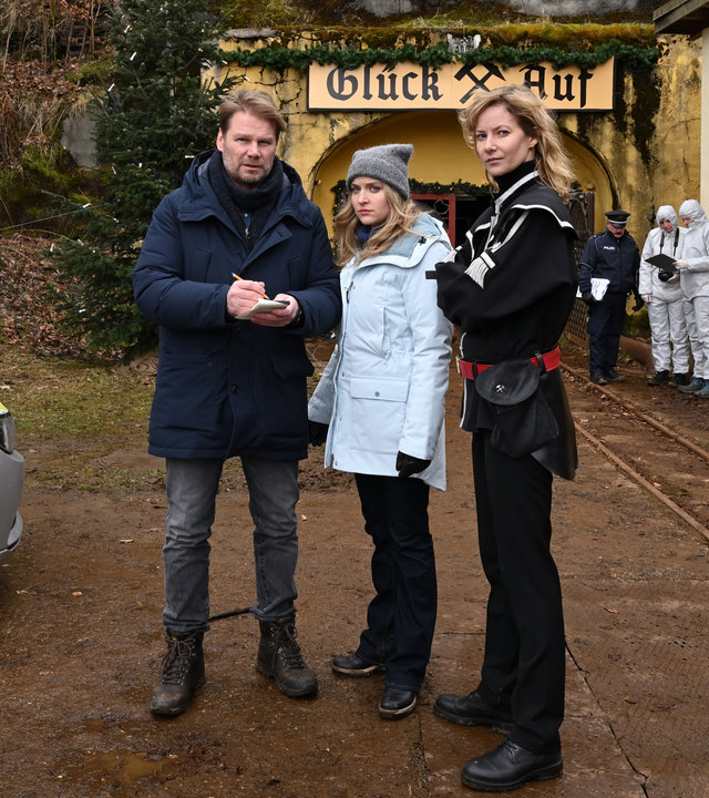 "Erzgebirgskrimi - Ein Mord zu Weihnachten": Robert Winkler (Kai Scheve), Karina Szabo (Lara Mandoki) und Saskia Bergelt (Teresa Weißbach) stehen vor einem Bergwerk. Es ist ein Polizeiauto zu sehen.