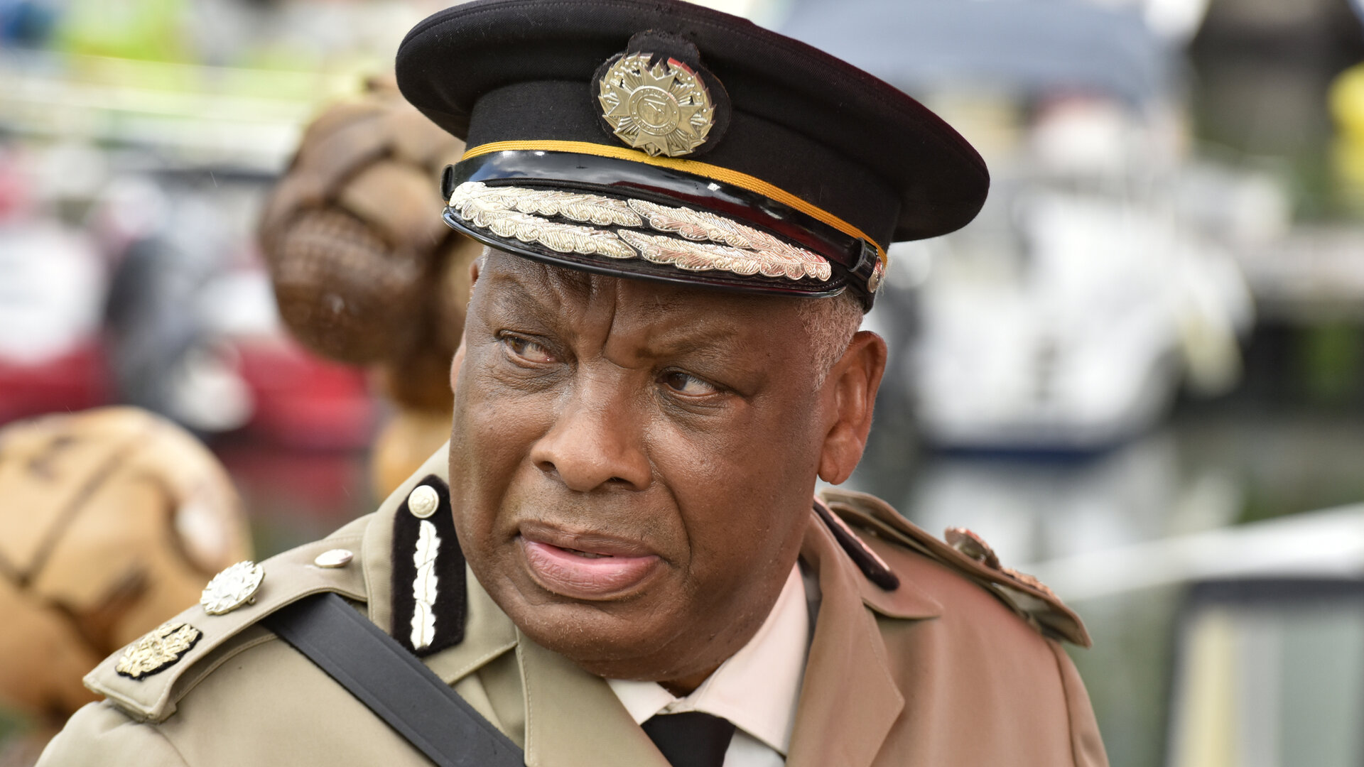 "Death in Paradise - Weihnachtsmänner in Gefahr": Commissioner Selwyn Patterson (Don Warrington) steht am Hafen. Er trägt eine helle Polizeiuniform sowie eine schwarze Dienstmütze. Kritisch blickt er zur Seite.