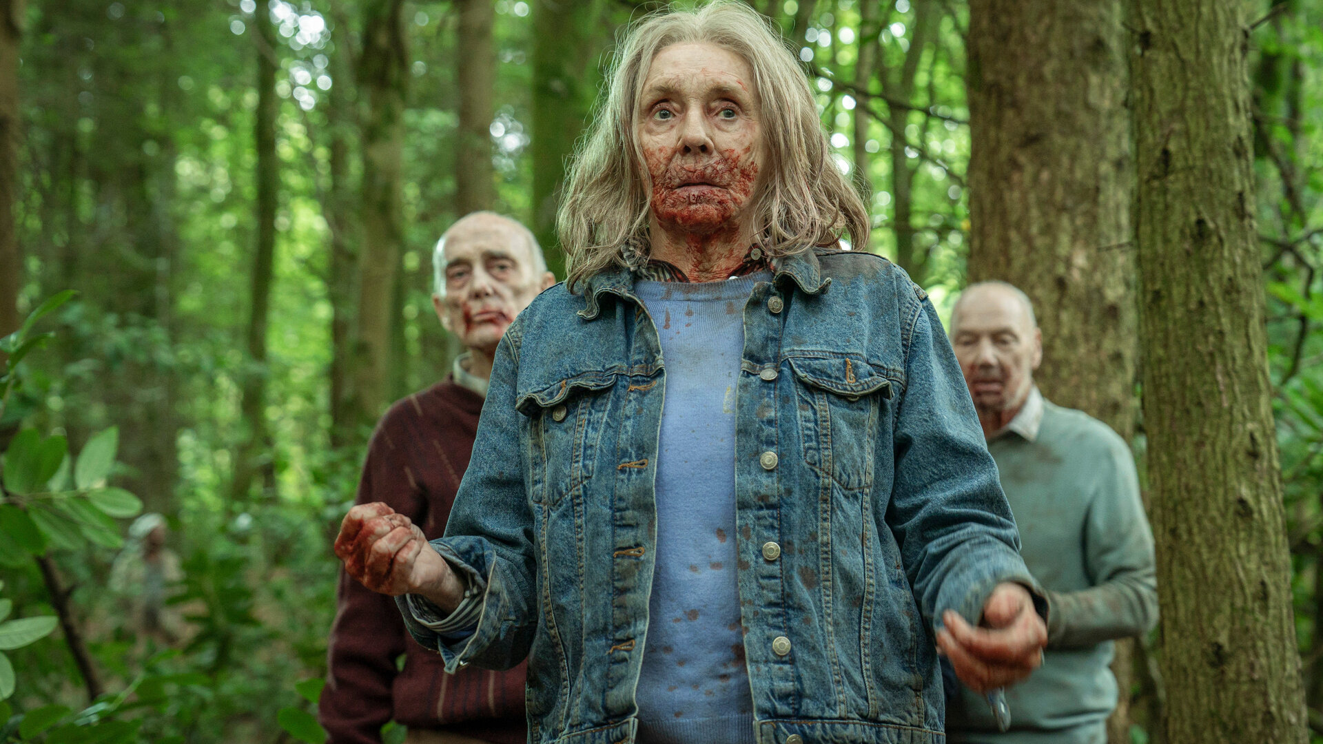 "Generation Z: Monsterparty": Cecily (Sue Johnston) geht durch einen Wald. Ihr Mund ist blutverschmiert. Hinter ihr sind weitere Senioren zu sehen.