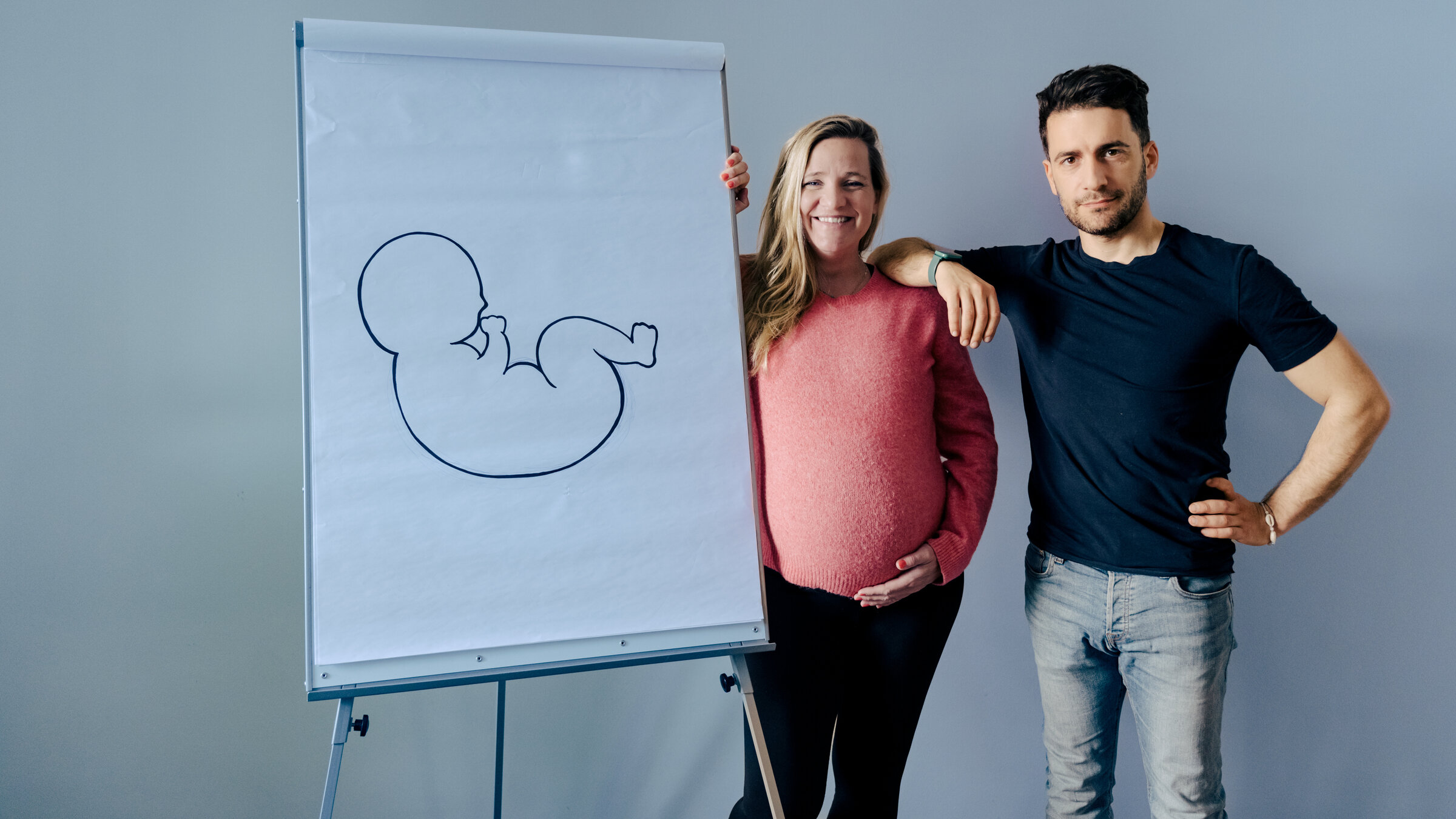 "37° Leben - Co-Parenting - Neue Wege zur Familie": Co-Eltern Sarah Dwinger und Filippo Lopes stehen neben einem Flipchart, auf dem der gezeichnete Umriss eines Babys zu sehen ist.