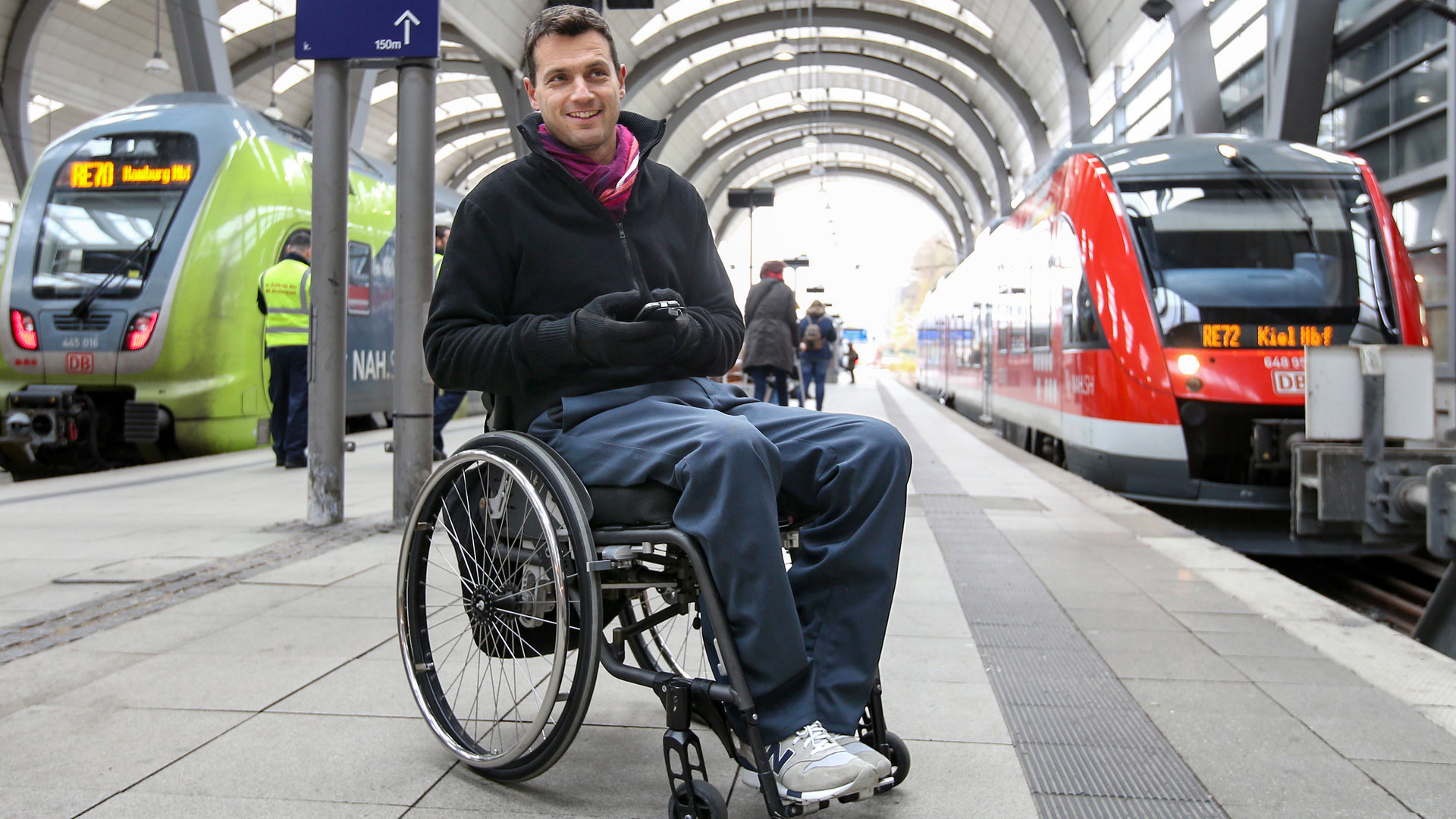 "einfach Mensch: Bahnfahren wie jede/r andere auch": Journalisten und Berufspendler Kay Macquarrie im Rollstuhl am Bahnsteig.