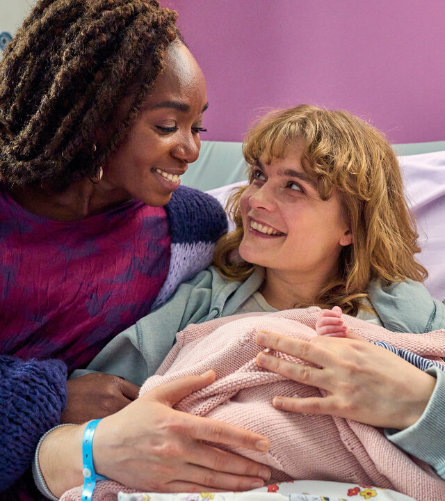 "BFF - Best Family Forever - SSW 42": Nikita (Karmela Shako) und Lena (Anna Schimrigk) sitzen auf dem Krankenhausbett und halten endlich ihr Baby im Arm. Beide lächeln glücklich.