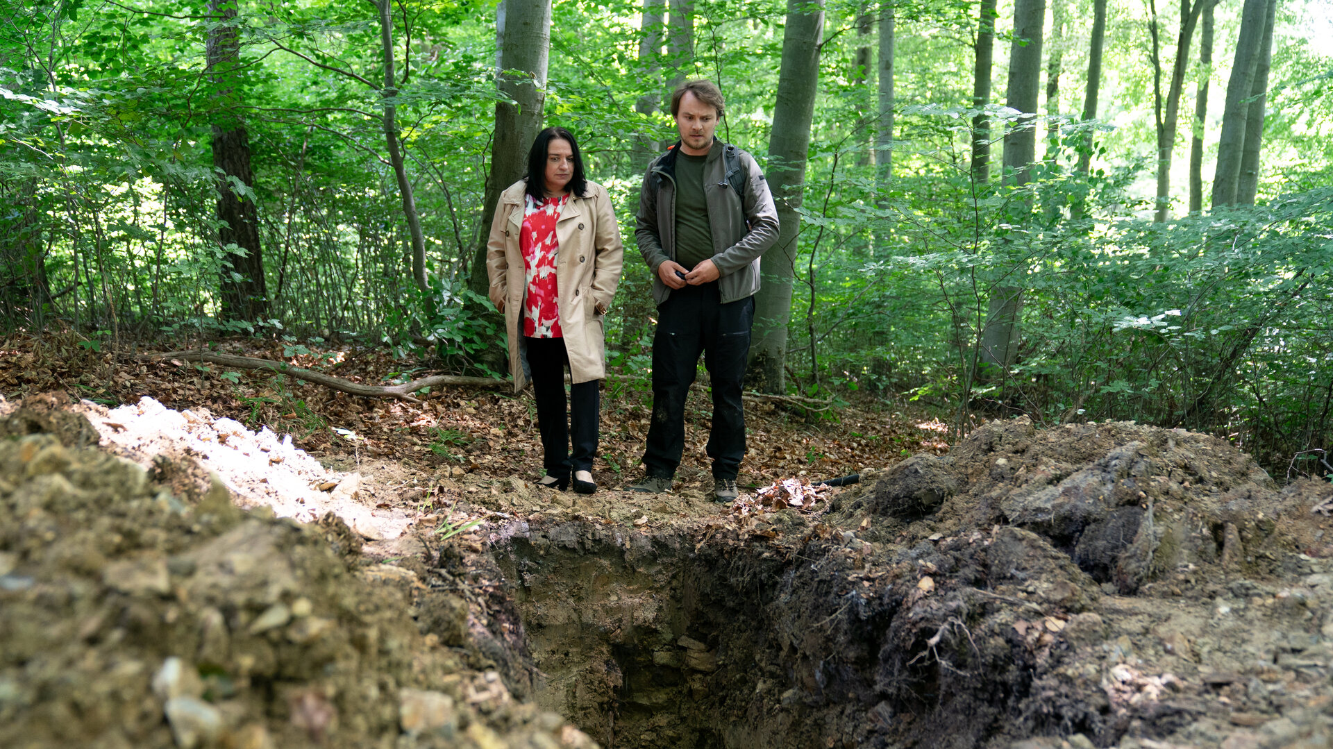 "SOKO Wien - Waldesruh": Spurensicherer Julius Rubatsch (Max Fischnaller) steht mit der Gerichtsmedizinerin Dr. Franziska Beck (Maria Happel) in einem Wald. Sie schauen in ein großes Loch im Boden.