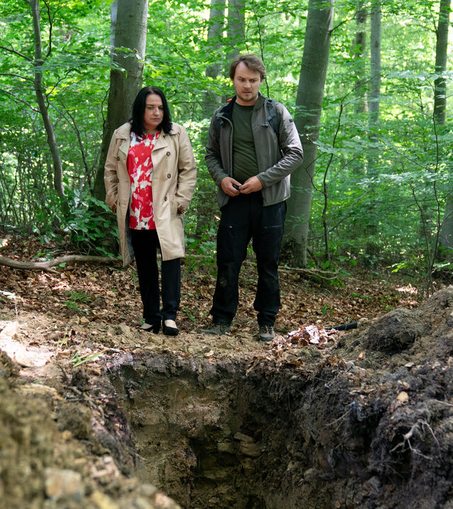 "SOKO Wien - Waldesruh": Spurensicherer Julius Rubatsch (Max Fischnaller) steht mit der Gerichtsmedizinerin Dr. Franziska Beck (Maria Happel) in einem Wald. Sie schauen in ein großes Loch im Boden.