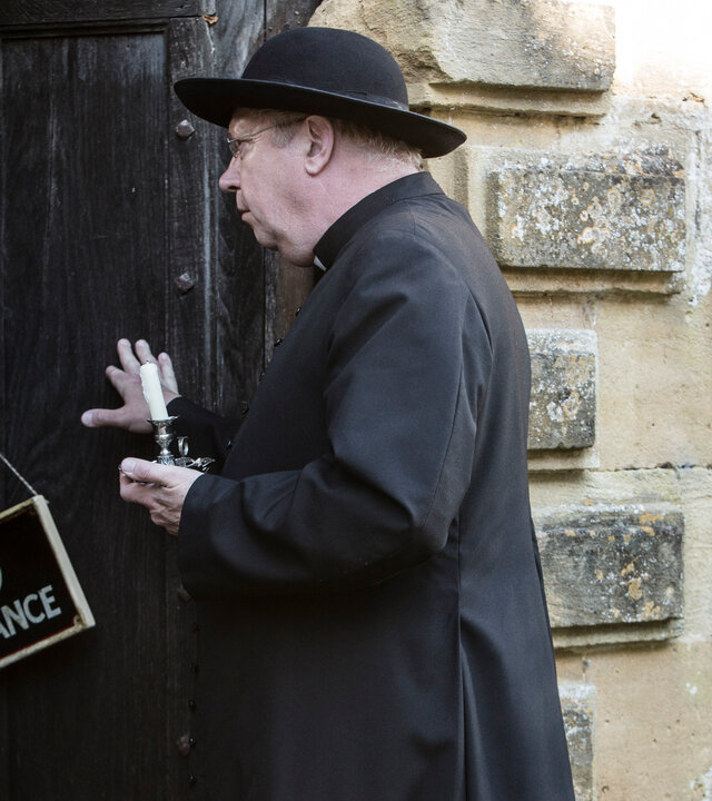 "Father Brown - Abschied von Lady Felicia": Father Brown (Mark Williams) hält mit einer Hand eine Holztür geöffnet, in der anderen hält er eine Kerze. An der Tür hängt ein Schild mit der Aufschrift ''No Admittance''.