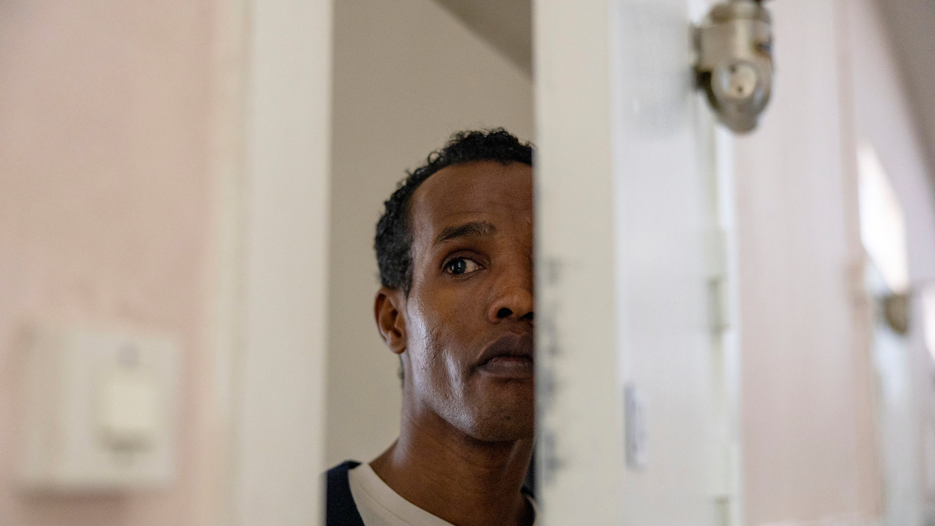 "Detective No. 24: Anna": Ibraahin (Nasir Farah Dhagole) steht in einer halb geöffneten Tür und beobachtet etwas.