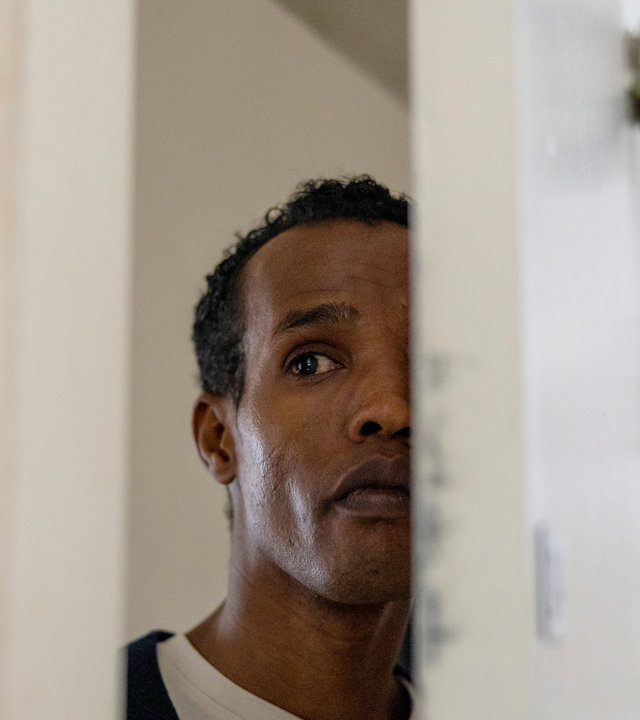 "Detective No. 24: Anna": Ibraahin (Nasir Farah Dhagole) steht in einer halb geöffneten Tür und beobachtet etwas.