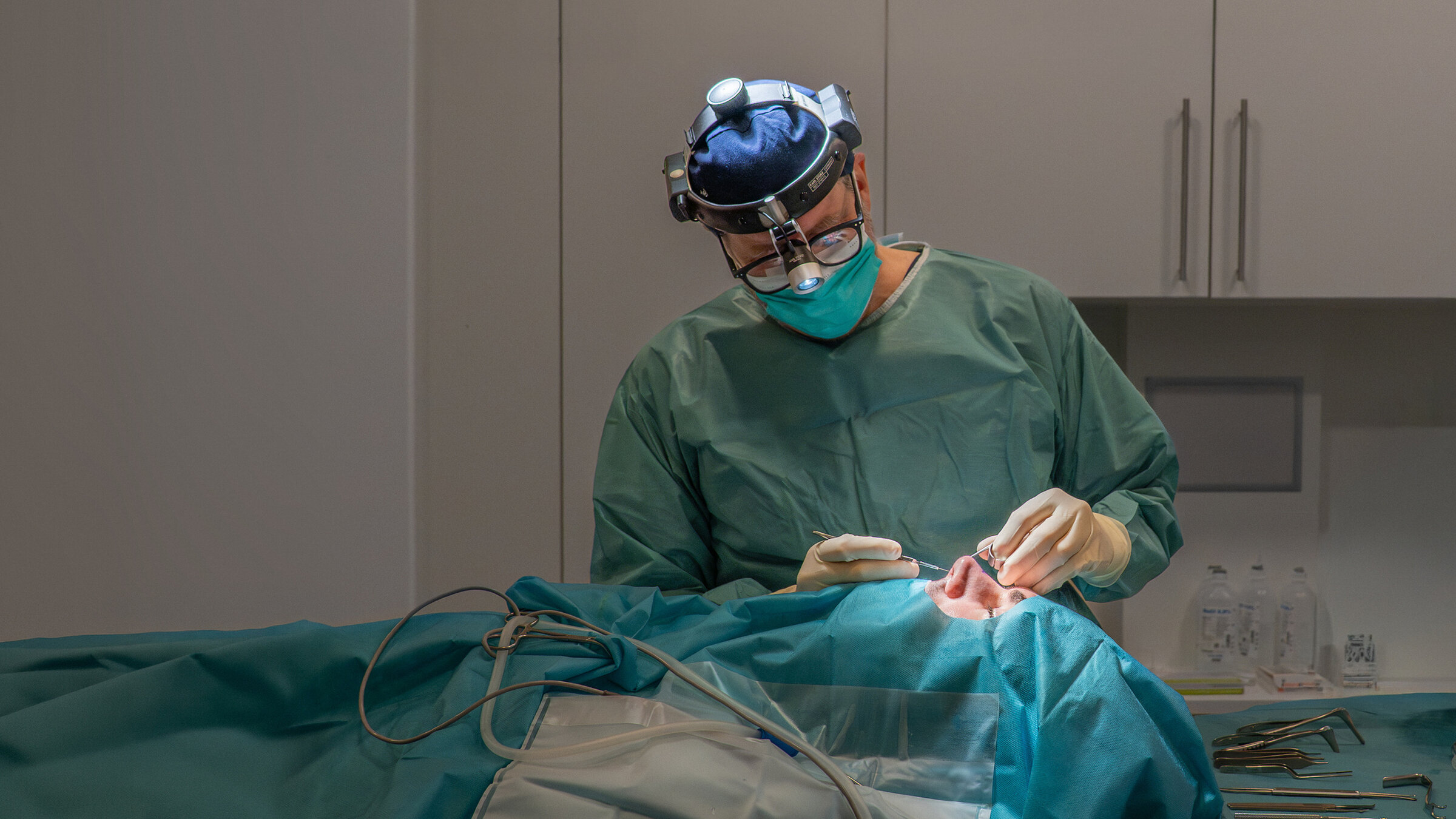 "37°Leben: Männer unterm Messer - Schönheit für ein neues Ich": Patient Paul Gressenberger liegt auf einer Liege, sein Körper ist verhüllt, nur ein Teil seines Gesichts schaut aus den Tüchern hervor. Professor Riedel beugt sich über ihn und greift mit einem Werkzeug an seine Nase.