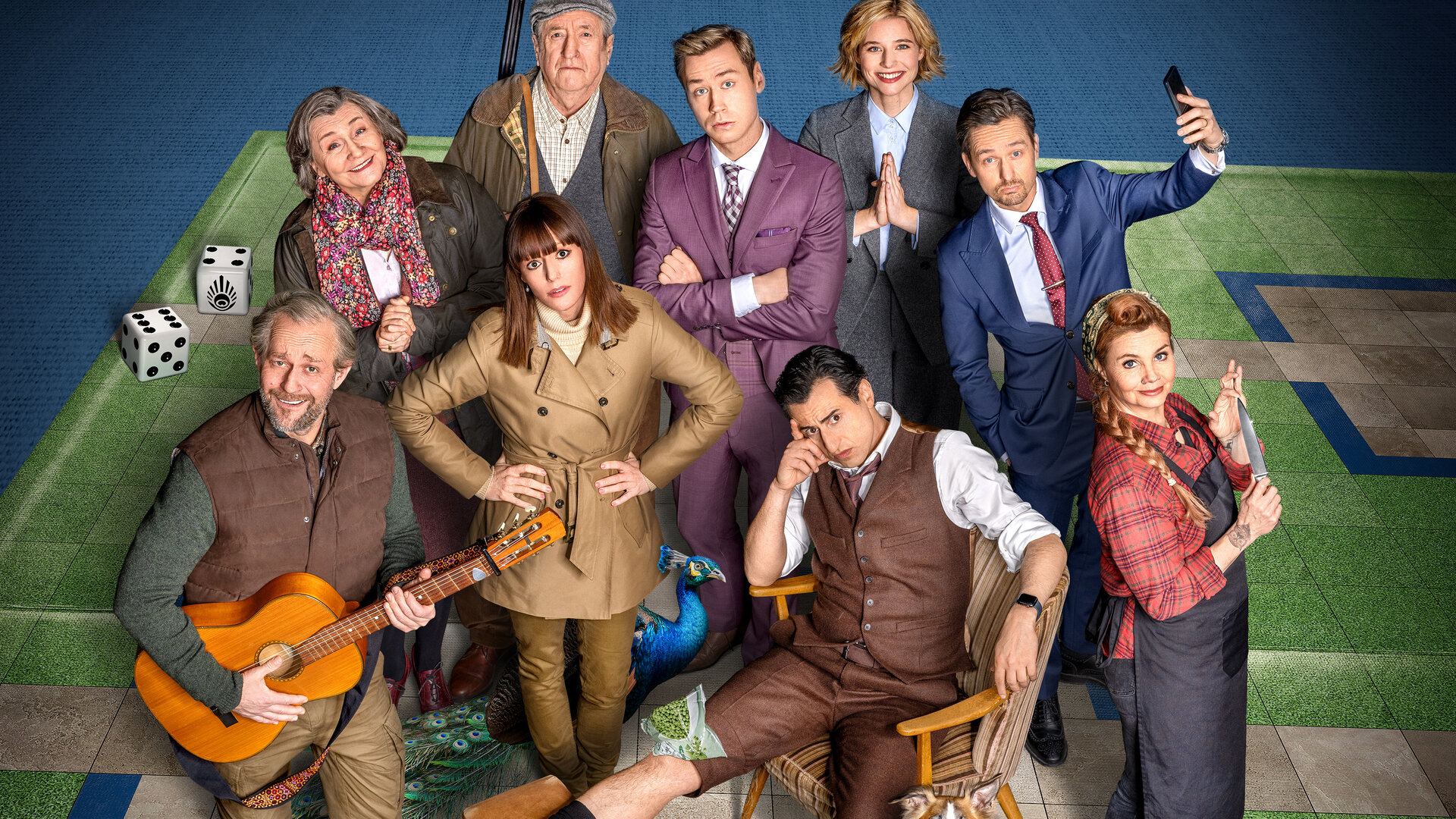 "Der Pfau": Artwork: Lord Hamish (Philip Jackson) und seine Gattin (Victoria Carling), David (David Kross), Andreas (Tom Schilling), Rebecca (Svenja Jung), Linda (Lavinia Wilson), Jim (Jürgen Vogel) und Bernhard (Serkan Kaya) stehen als Gruppe auf einer mit Kunstrasen bedeckten Fläche und schauen in die Kamera. Jim hält seine Gitarre in der Hand, und Bernhard sitzt mit hochgelegtem Bein auf einem Stuhl daneben.