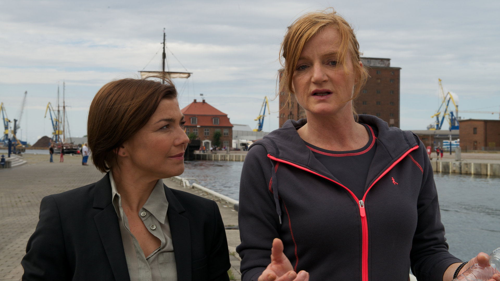"SOKO Wismar - Meine beste Freundin": Ermittlerin Katrin Börensen (Claudia Schmutzler) läuft neben der Münchener Staatsanwältin Silvia Vandenberg (Nina Petri) her und hört ihr aufmerksam zu. Im Hintergrund ist der Hafen von Wismar zu sehen.