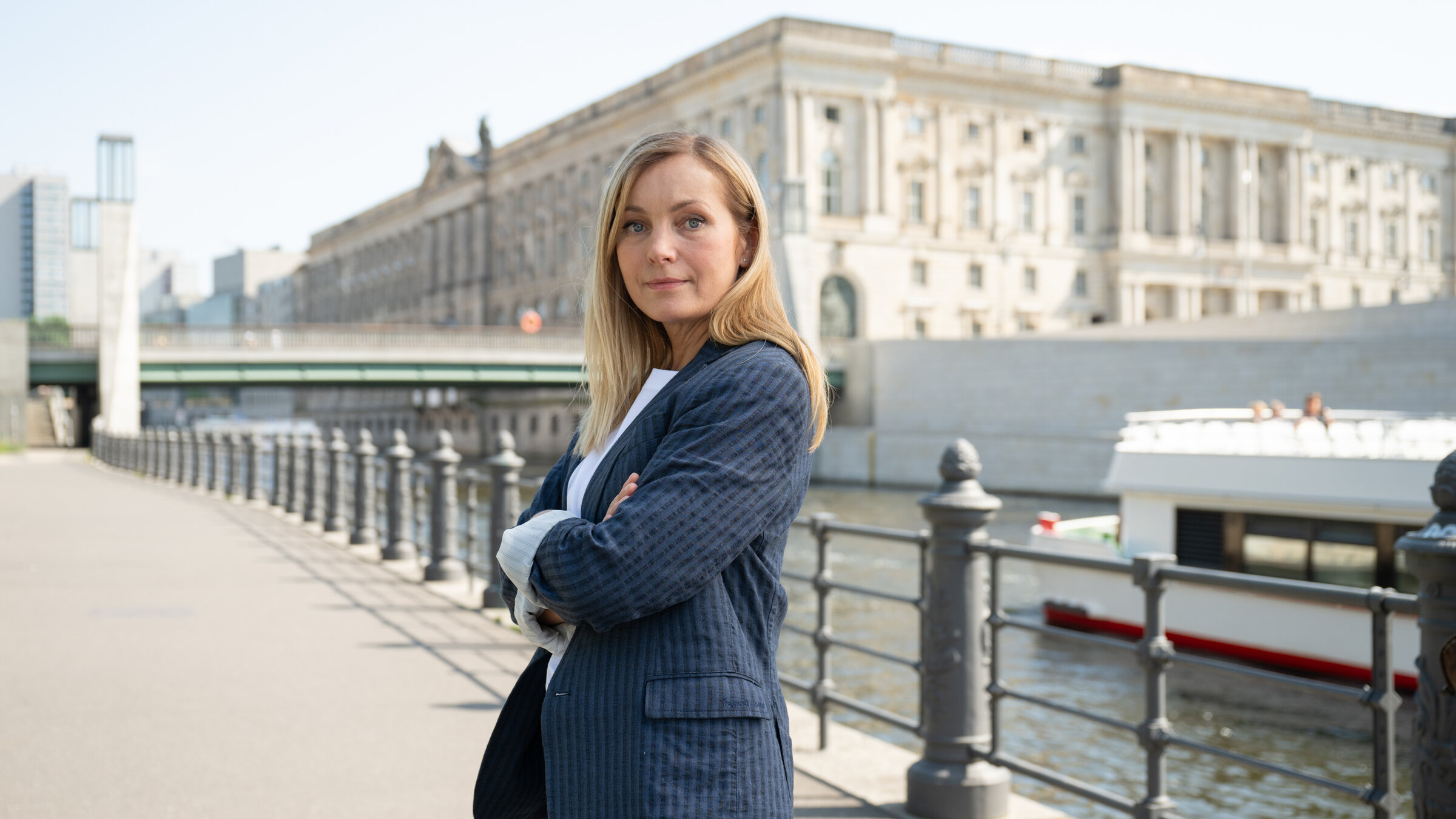 "Die Jägerin - Gegen die Wut": Staatsanwältin Judith Schrader (Nadja Uhl) steht mit verschränkten Armen im Freien vor der Spree. Im Hintergrund steht die Berliner Rathausbrücke.