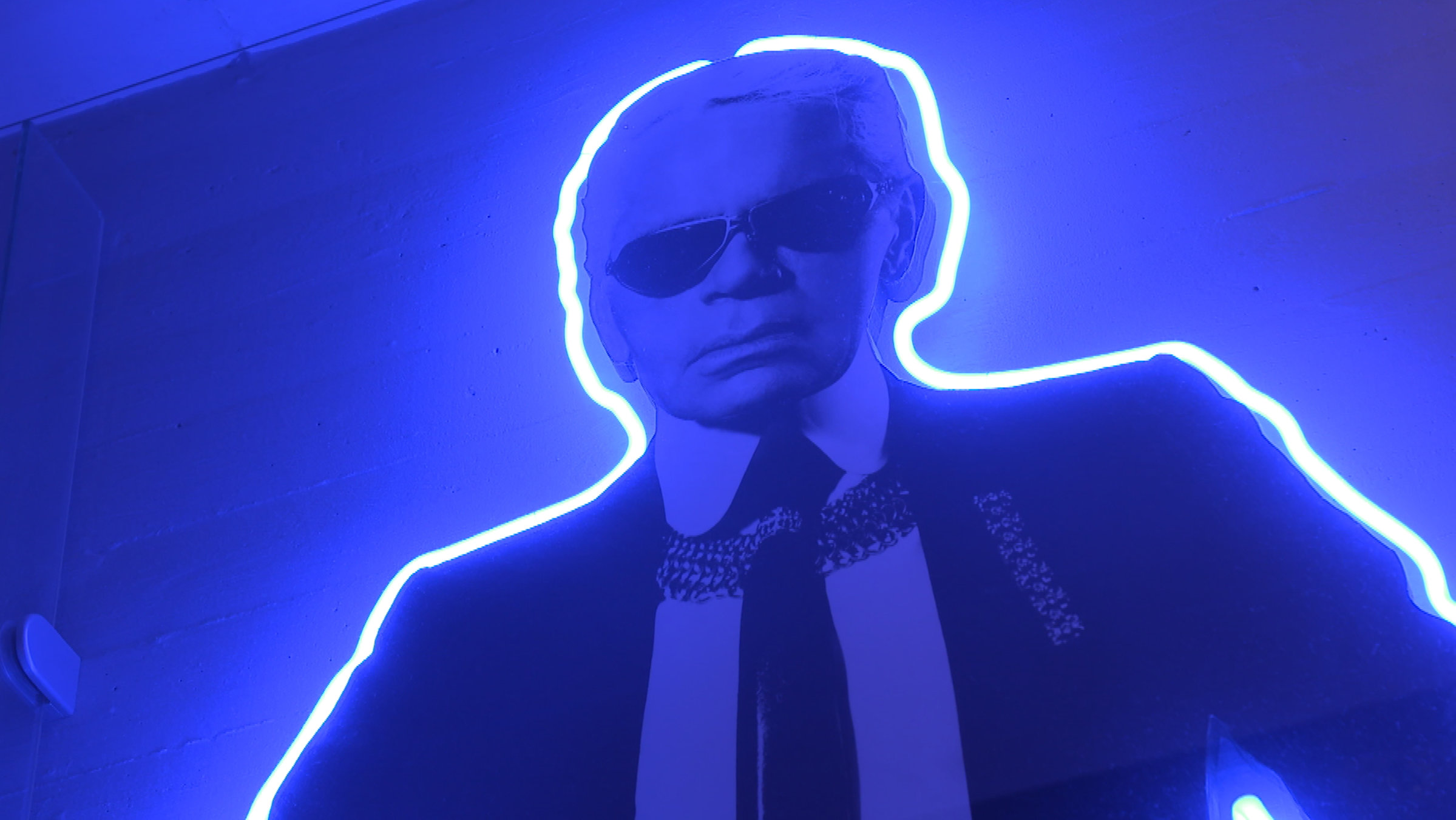 "ZDF-History: Karl Lagerfeld - Eine deutsche Legende": Die Umrisse von Karl Lagerfeld sind von einer blau leuchtenden Neonröhre nachgezeichnet. Das komplette Bild ist in blaues Licht getaucht.