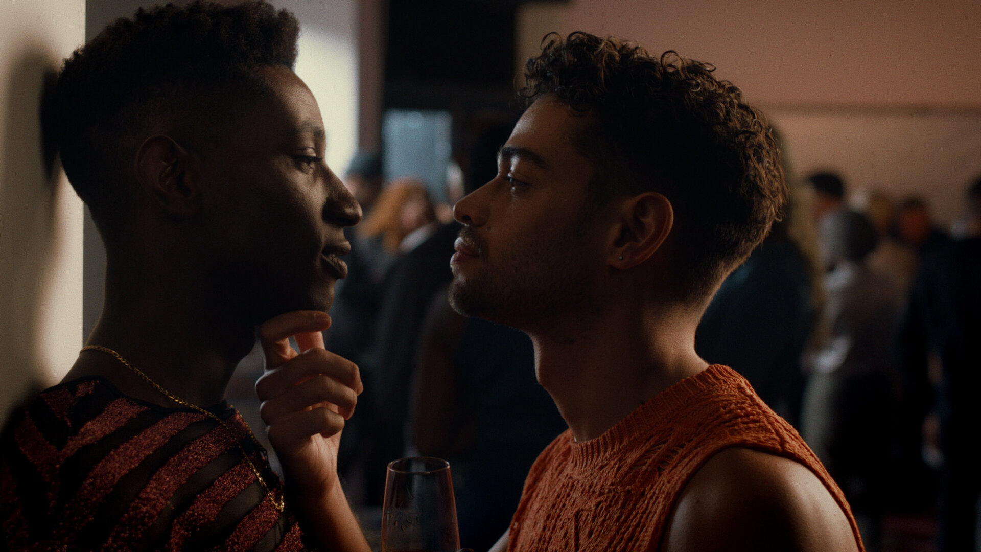 "House of Bellevue - Sex Siren": Emm (Ricco-Jarret Boateng) lehnt an der Wand und sieht João (Robin Cadet) tief in die Augen, der nah vor ihm steht und sein Kinn mit den Fingern festhält.