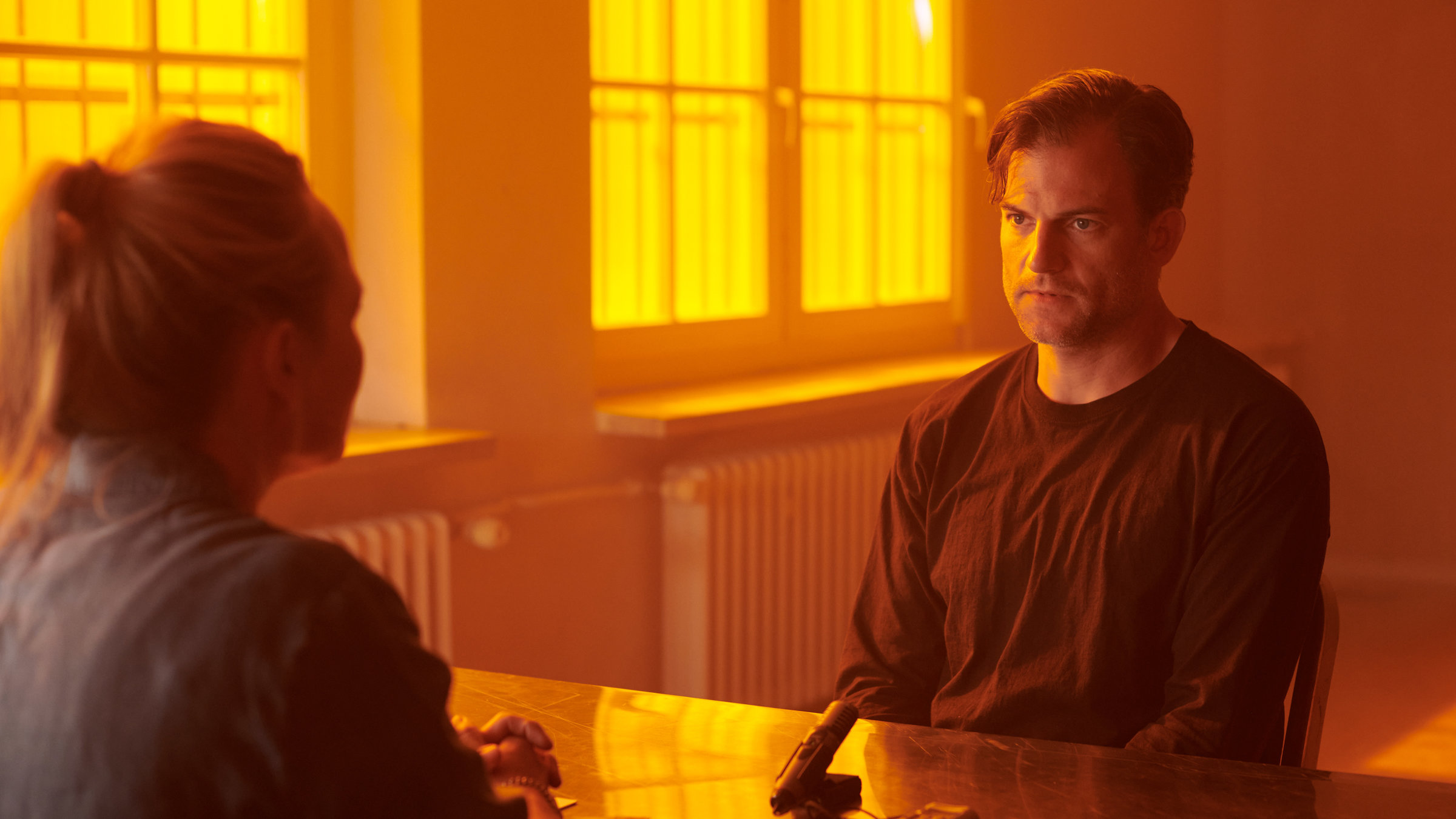 "Gestern waren wir noch Kinder (4)": Peter Klettmann (Torben Liebrecht) sitzt im Verhör bei Kommissarin Jana Lebowski (Anja Schneider). Die beiden sitzen sich am Tisch gegenüber, auf dem ein Mikrofon steht.