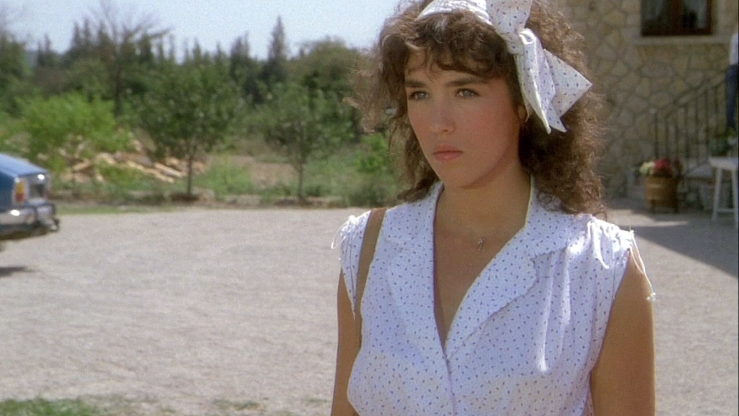 "Ein mörderischer Sommer": Eliane Wieck (Isabelle Adjani) steht auf dem Hof eines Anwesens, sie trägt ein ärmelloses helles Sommerkleid und ein Haarband aus demselben Stoffmuster.