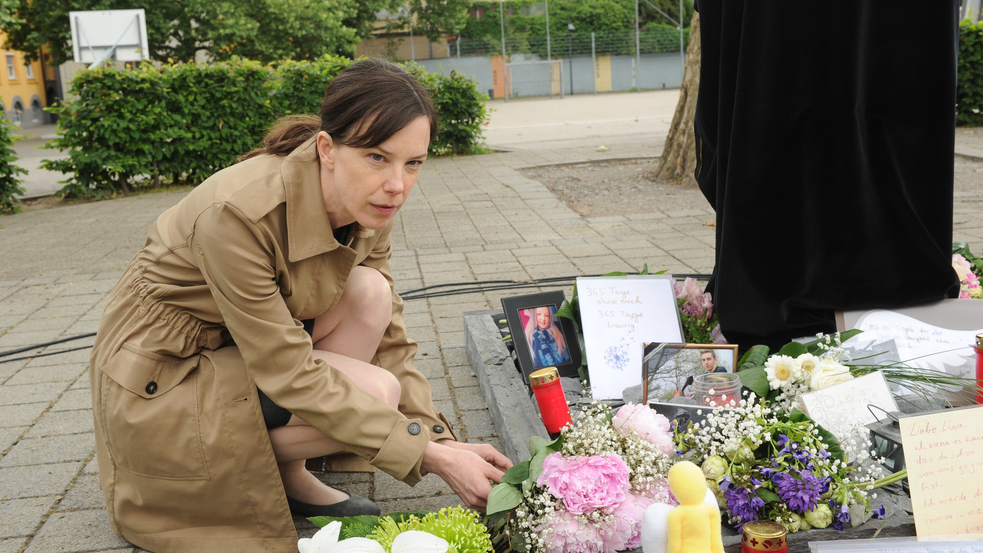 "SOKO Stuttgart - Sühne": An der Gedenkstätte für die verstorbenen Schüler legt Johanna Lehmann (Anne von Keller) einen Blumenstrauß zu den bereits vorhandenen Kerzen, Sträußen, Briefen und Bildern nieder.