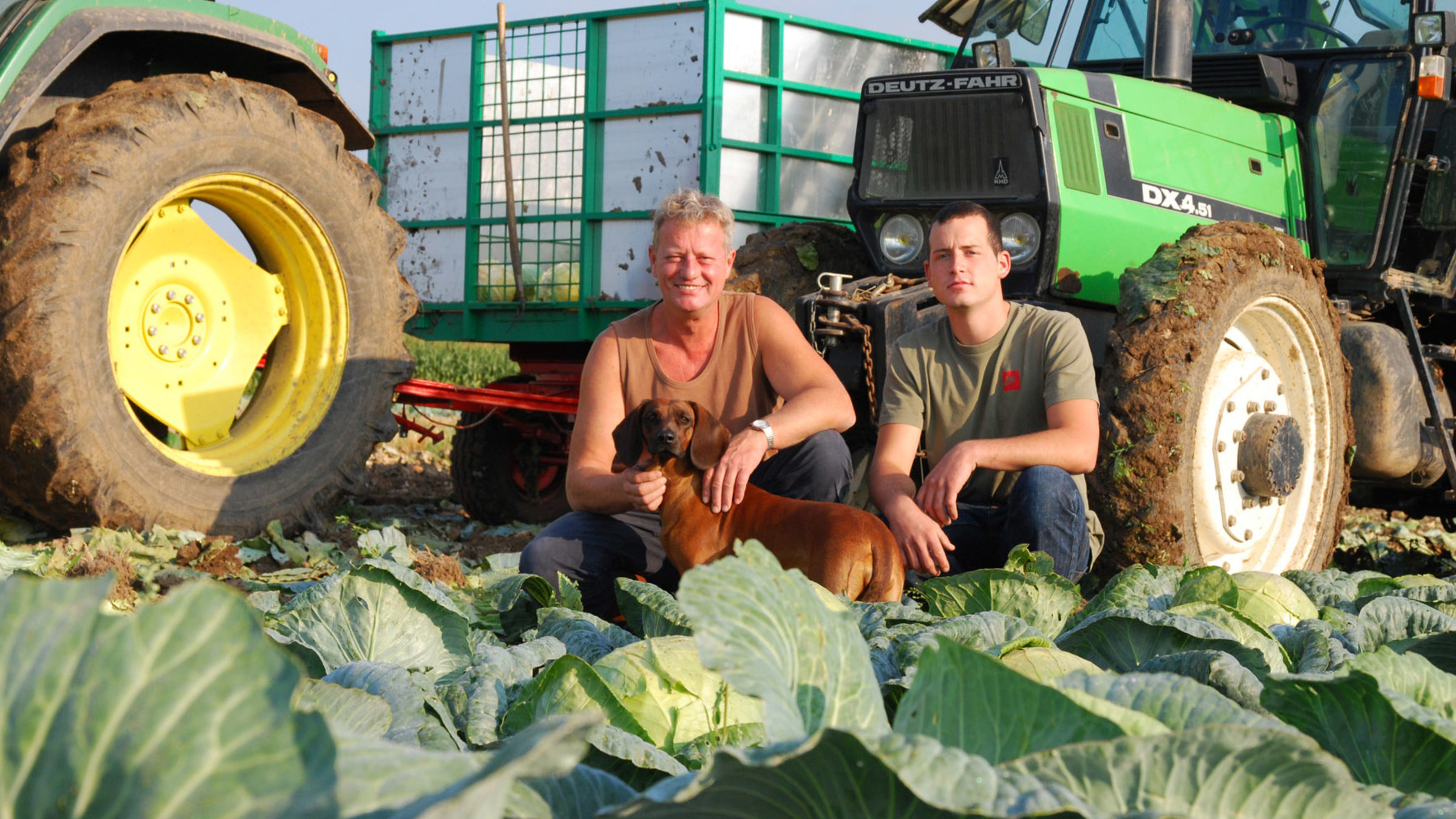 "Zu Tisch im Elsass": Vater Jean-Michel Ades (links) mit seinem ältesten Sohn Florent knien im Feld, dahinter zwei Traktoren.