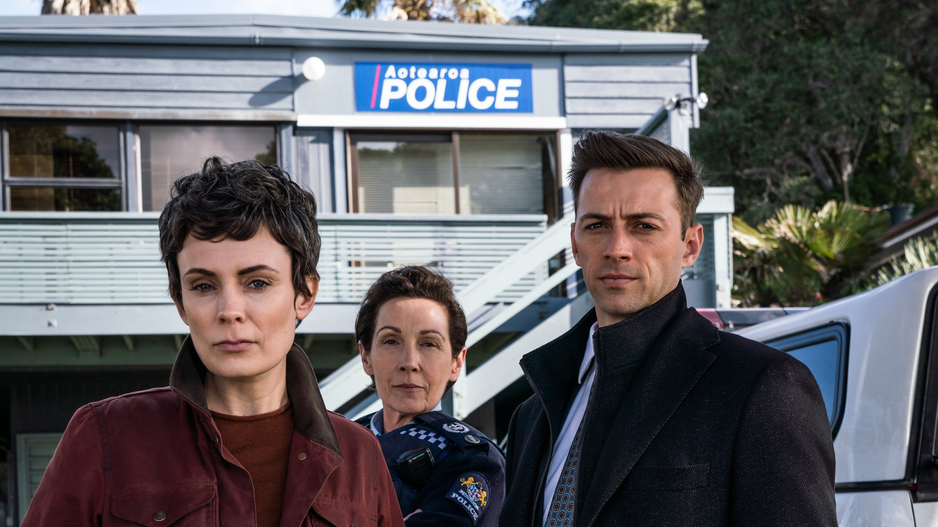 "Auckland Detectives - Tödliche Bucht: Enttarnung": Detective Senior Sergeant Jessica Savage (Kate Elliott), ihr Kollege Detective Sergeant Justin Harding (Ido Drent) und Senior Sergeant Denise Abernethy (Alison Bruce) stehen in Nahaufnahme vor der Polizeistation in Waiheke.