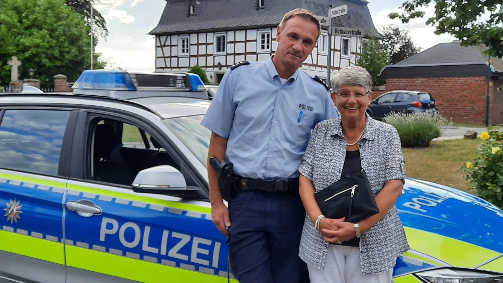 "Terra Xpress - Falsche Polizisten und andere Betrügereien": Die Rentnerin Rose-Marie Schmidt steht mit einem Polizisten vor dessen Dienstwagen. Die beiden lächeln freundlich in die Kamera.