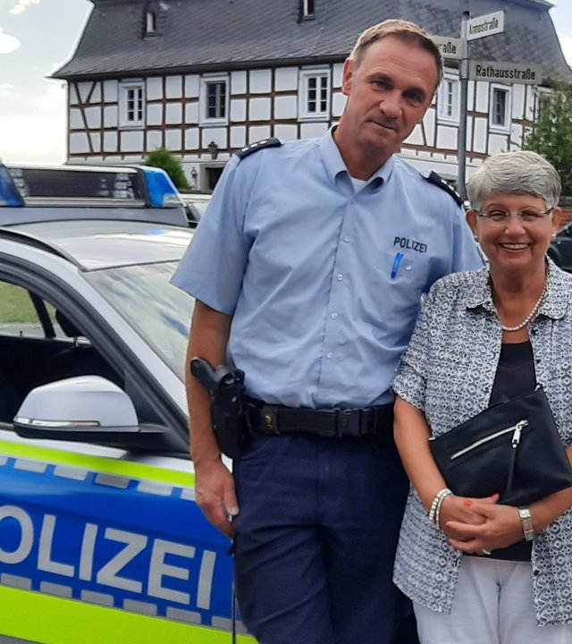 "Terra Xpress - Falsche Polizisten und andere Betrügereien": Die Rentnerin Rose-Marie Schmidt steht mit einem Polizisten vor dessen Dienstwagen. Die beiden lächeln freundlich in die Kamera.