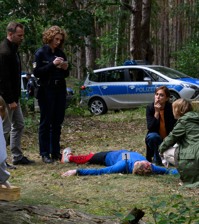 „SOKO Wismar – Der Berg ruft“: Dr. Helene Sturbeck (Katharina Blaschke), Paula Moorkamp (Stella Hinrichs), Lars Pöhlmann (Dominic Boeer) und Karoline Joost (Nike Fuhrmann) haben sich um den toten Toni Leitner (Christoph von Friedl) im Wald versammelt. Roswitha Prinzler (Silke Matthias) sucht nach Spuren.