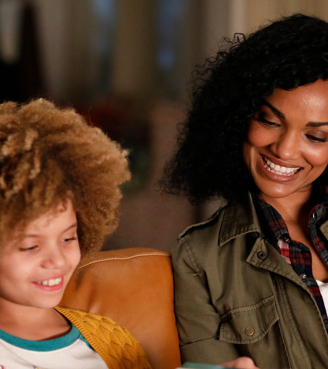 "The Rookie - Nachts": Nyla Harper (Mekia Cox) sitzt mit ihrer Tochter Lila (Carsyn Rose) auf der Couch und liest in einem Buch.