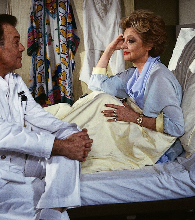 "Die Schwarzwaldklinik - Der Infarkt": Vanessa Bodenstedt (Nadja Tiller) sitzt im Krankenbett und spricht mit Prof. Brinkmann (Klausjürgen Wussow).