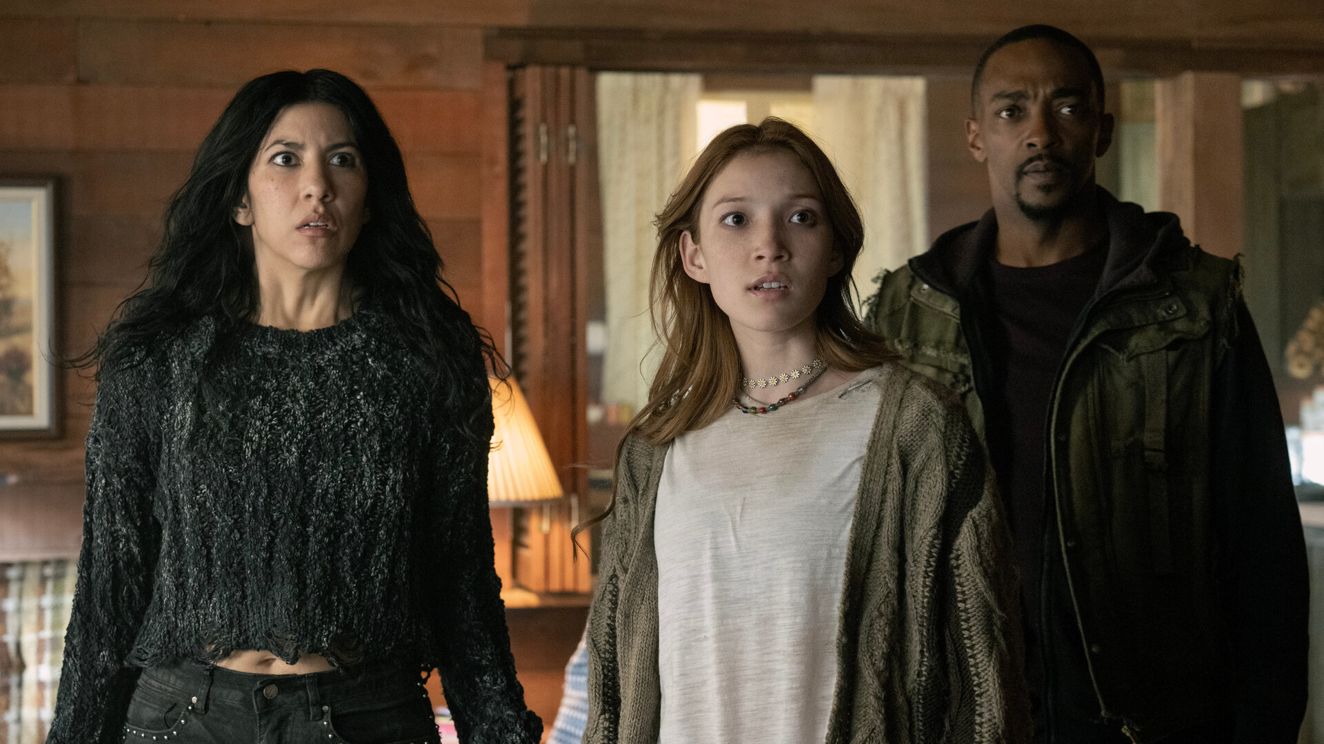 "Twisted Metal - NUY3ARZ": In einem Wohnzimmer stehen Quiet (Stephanie Beatriz), Mayhem (Saylor Bell Curda) und John (Anthony Mackie) nebeneinander. Alle drei blicken geschockt nach vorne.