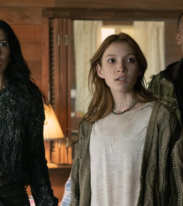 "Twisted Metal - NUY3ARZ": In einem Wohnzimmer stehen Quiet (Stephanie Beatriz), Mayhem (Saylor Bell Curda) und John (Anthony Mackie) nebeneinander. Alle drei blicken geschockt nach vorne.