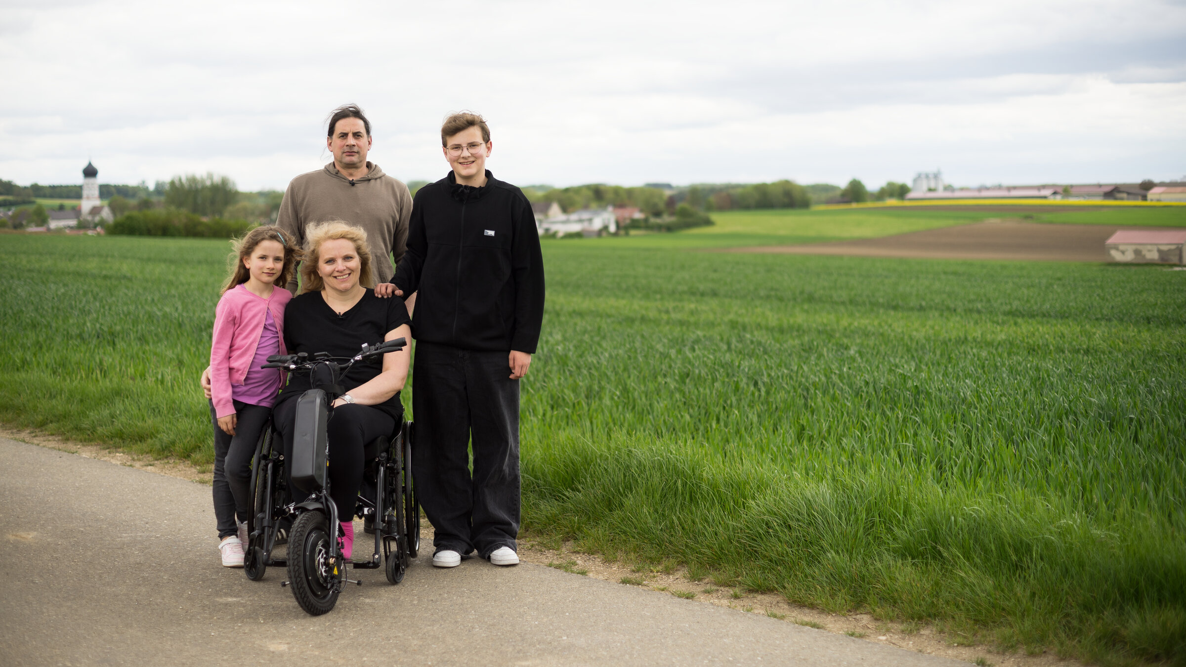 "Einfach Mensch - Mütter mit Behinderung": Am Feldrand: Kerstin Rathgeb sitzt im Rollstuhl, ihre zwei Kinder und ihr Mann stehen daneben.