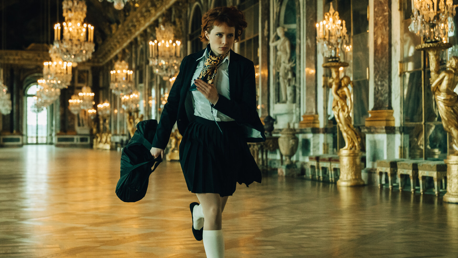 "Cat's Eyes - Alexia": Alexia (Claire Romain) läuft durch einen Saal in einem barock ausgestatteten Gebäude. Sie trägt eine Uniform mit kurzem Rock und Kniestrümpfen.
