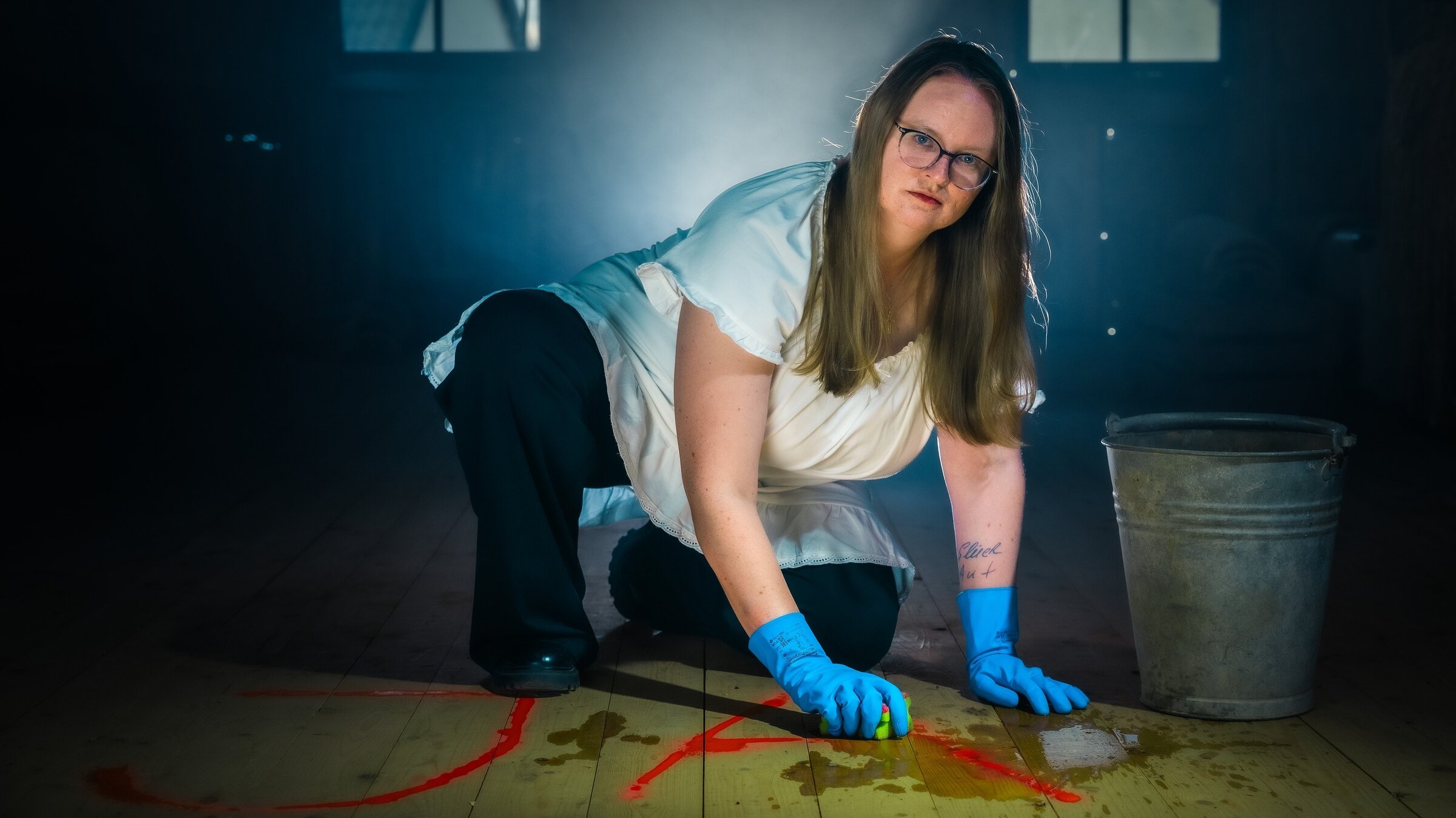 "37Â°Leben - Against all Gods: DÃ¼rfen wir Gott spielen?â: Laura kniet auf dem Boden und putzt mit Handschuhen ein Ja vom Boden. Dabei schaut sie ernst in die Kamera.