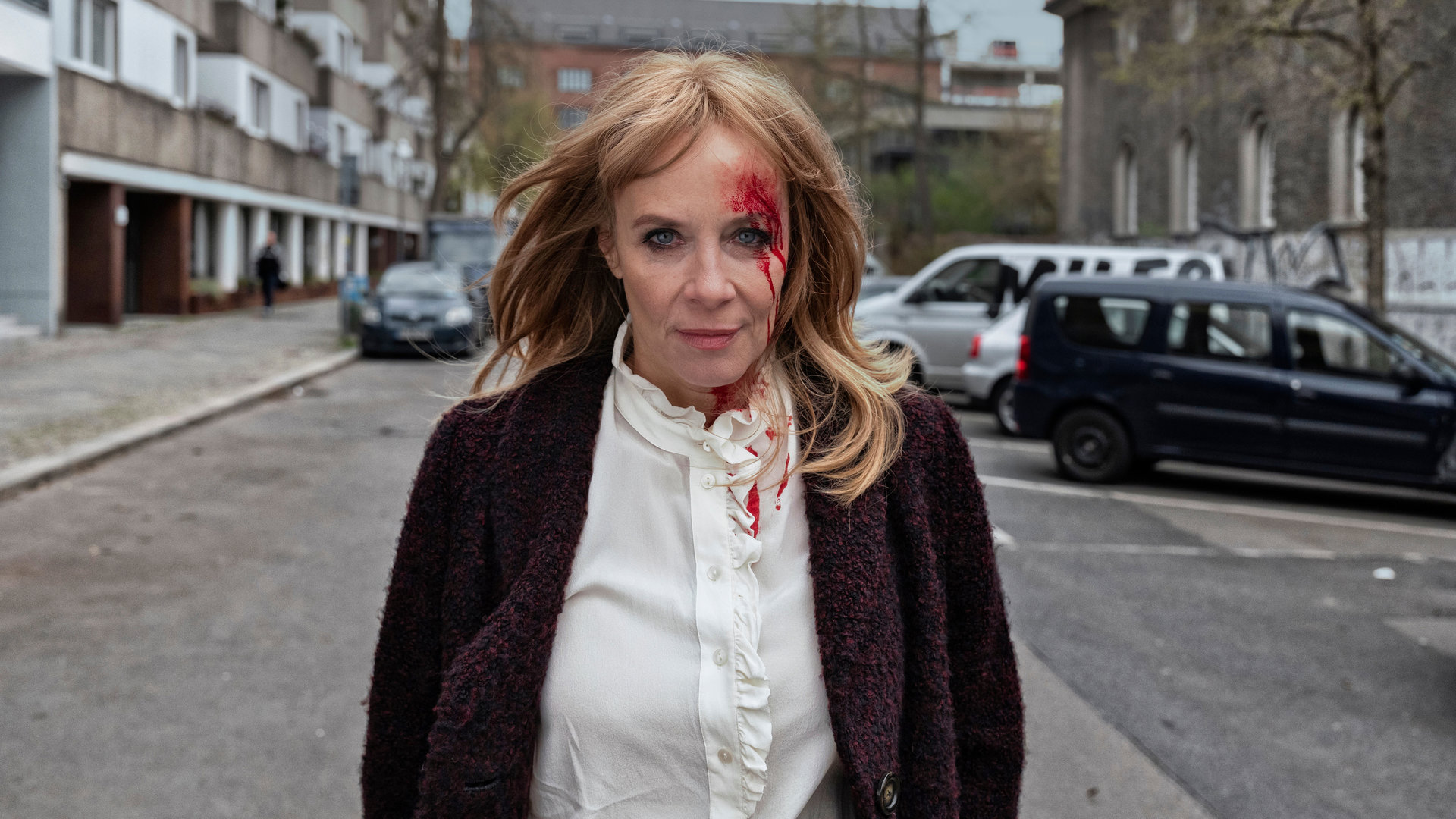 "Der Überfall - Sonnabend: Zwischen Leben und Tod": Paula Schönberg (Katja Riemann) läuft allein eine Straße herunter. Sie hat eine blutende Verletzung im Gesicht.