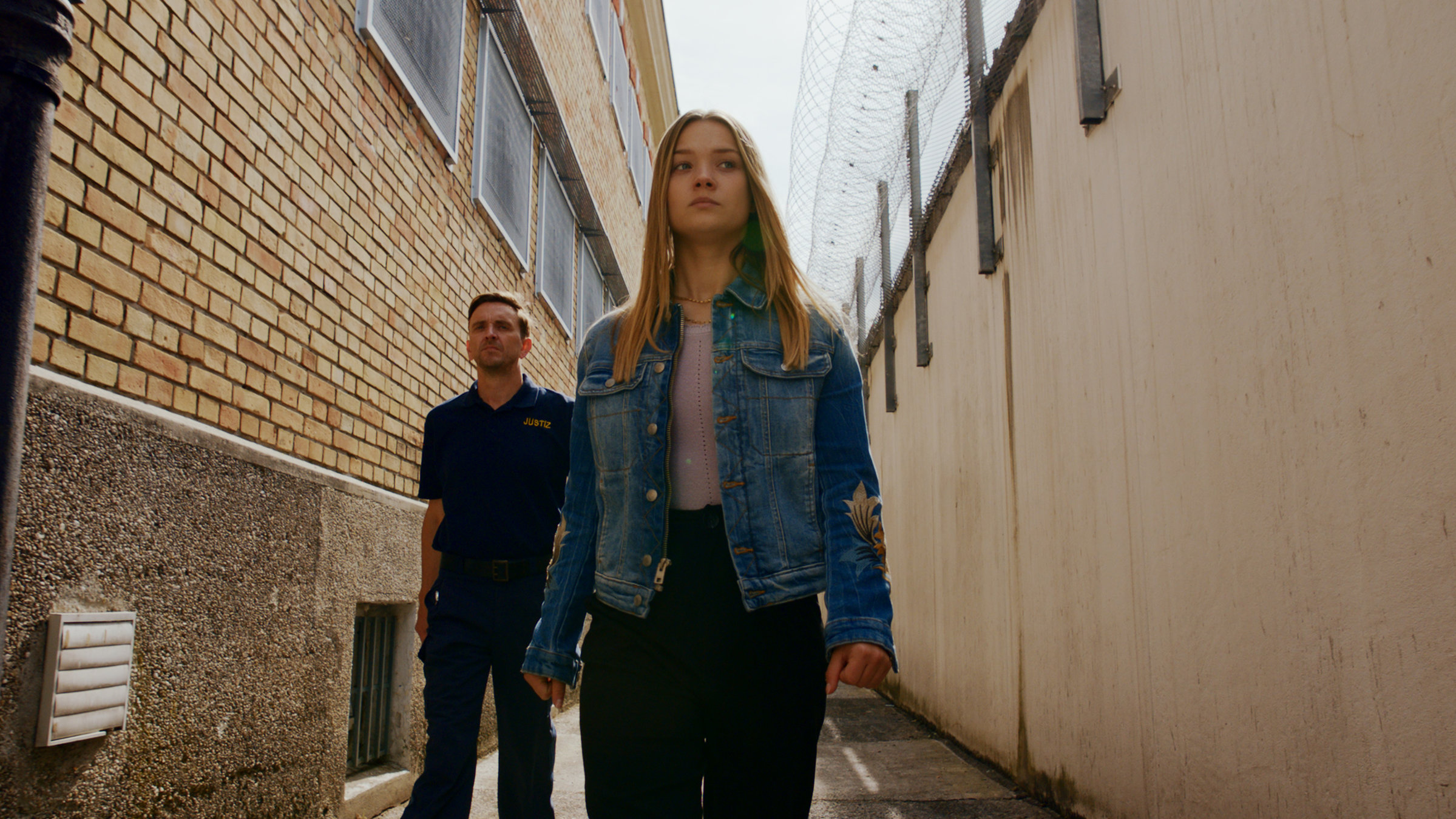"Gestern waren wir noch Kinder (5)": Vivi Klettmann (Julia Beautx) ist auf dem Weg ins Gefängnis. Ihr Blick ist traurig, aber dennoch gefasst. Sie wird von einem Gefängniswärter begleitet.