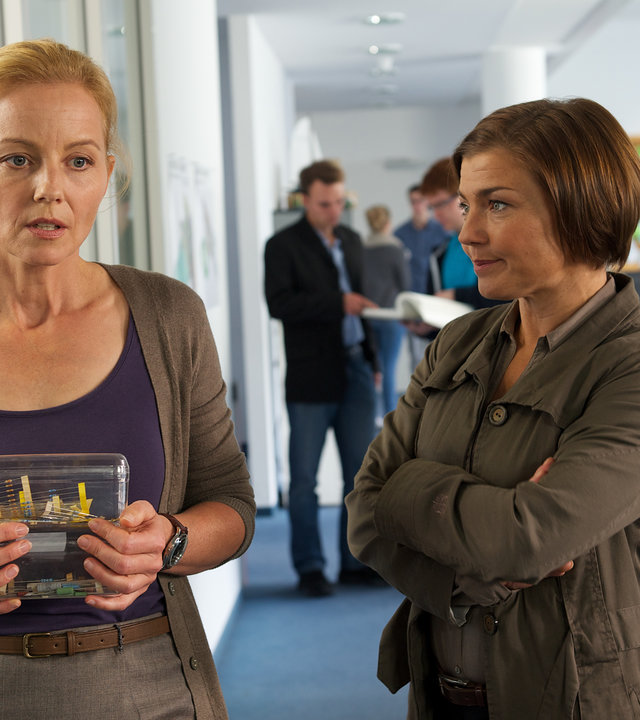 "SOKO Wismar - Der letzte Aufguss": Melanie Meyer (Carina Wiese) steht in einem Flur bei Katrin Börensen (Claudia Schmutzler) und ist sichtlich angespannt. Katrin Börensen hat die Hände vor der Brust verschränkt und schaut Melanie an.
