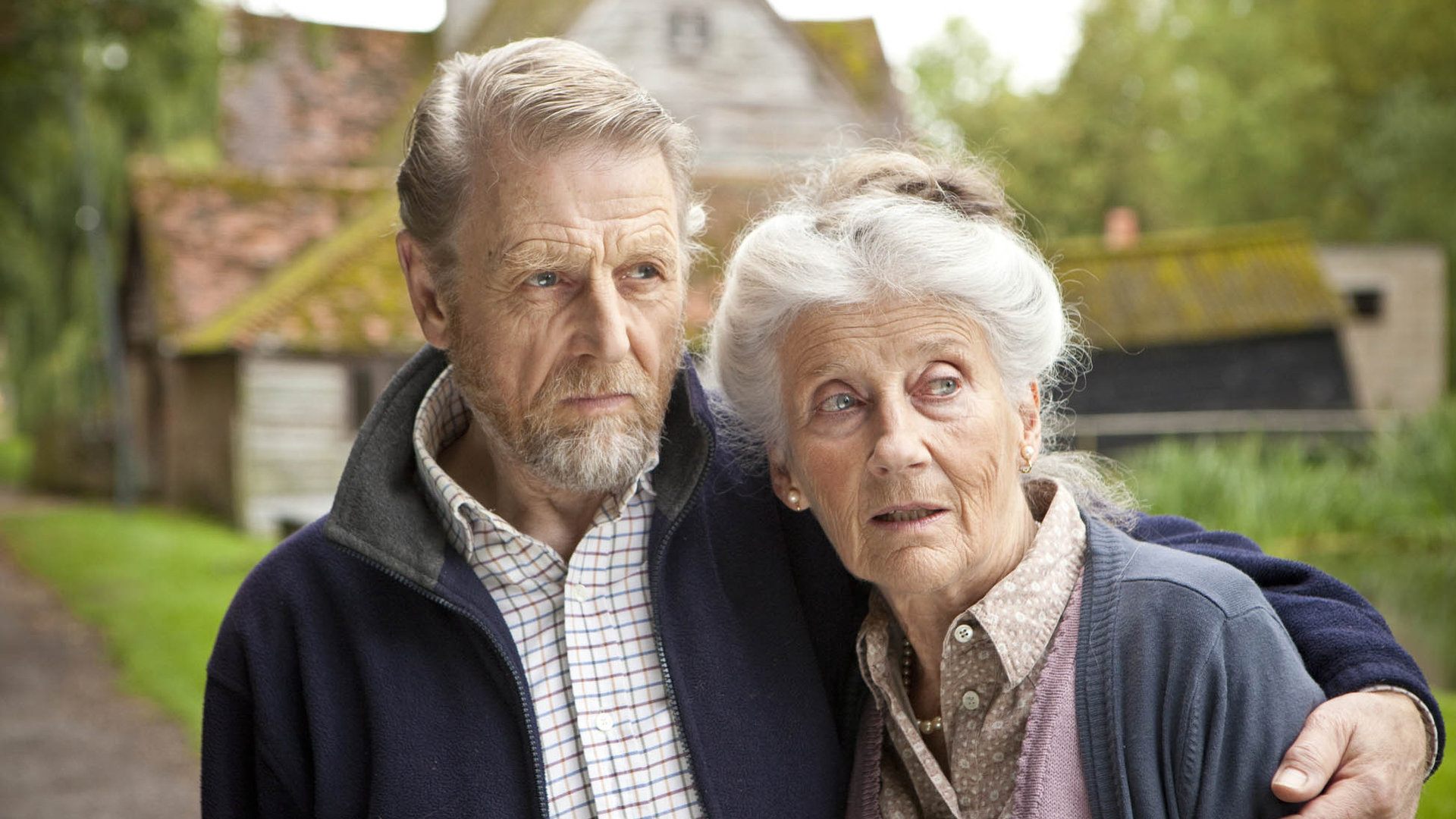 "Inspector Barnaby": Mr. Bingham ist nicht zu sprechen": William Bingham (Edward Fox) und seine Frau Mary (Phyllida Law) stehen eng aneinandergeschmiegt. Er hat seinen Arm um sie gelegt. Im Hintergrund sieht man ein älteres Wohngebäude.