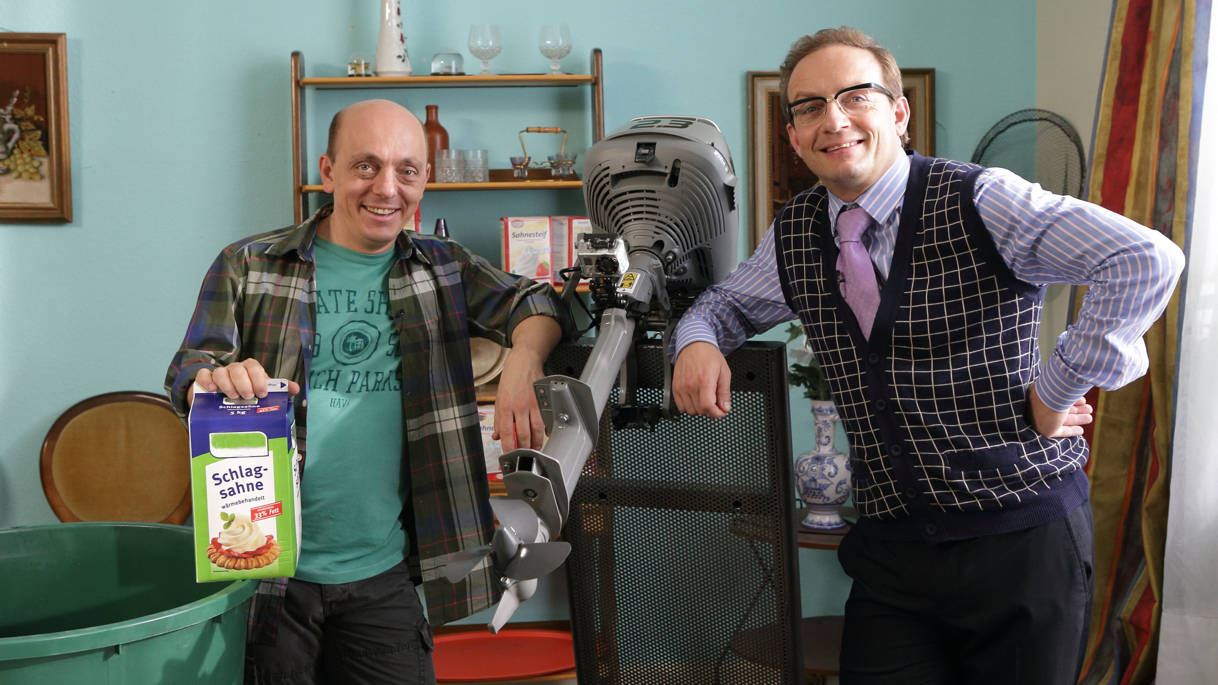 "Nicht Nachmachen": Bernhard Hoëcker und Wigald Boning stehen nebeneinander, zwischen ihnen ein Außenbordmotor, der an einer Vorrichtung fixiert ist. Bernhard Hoëcker hält eine Riesenpackung Schlagsahne in der Hand. Im Vordergrund ein großer Plastikbottich.