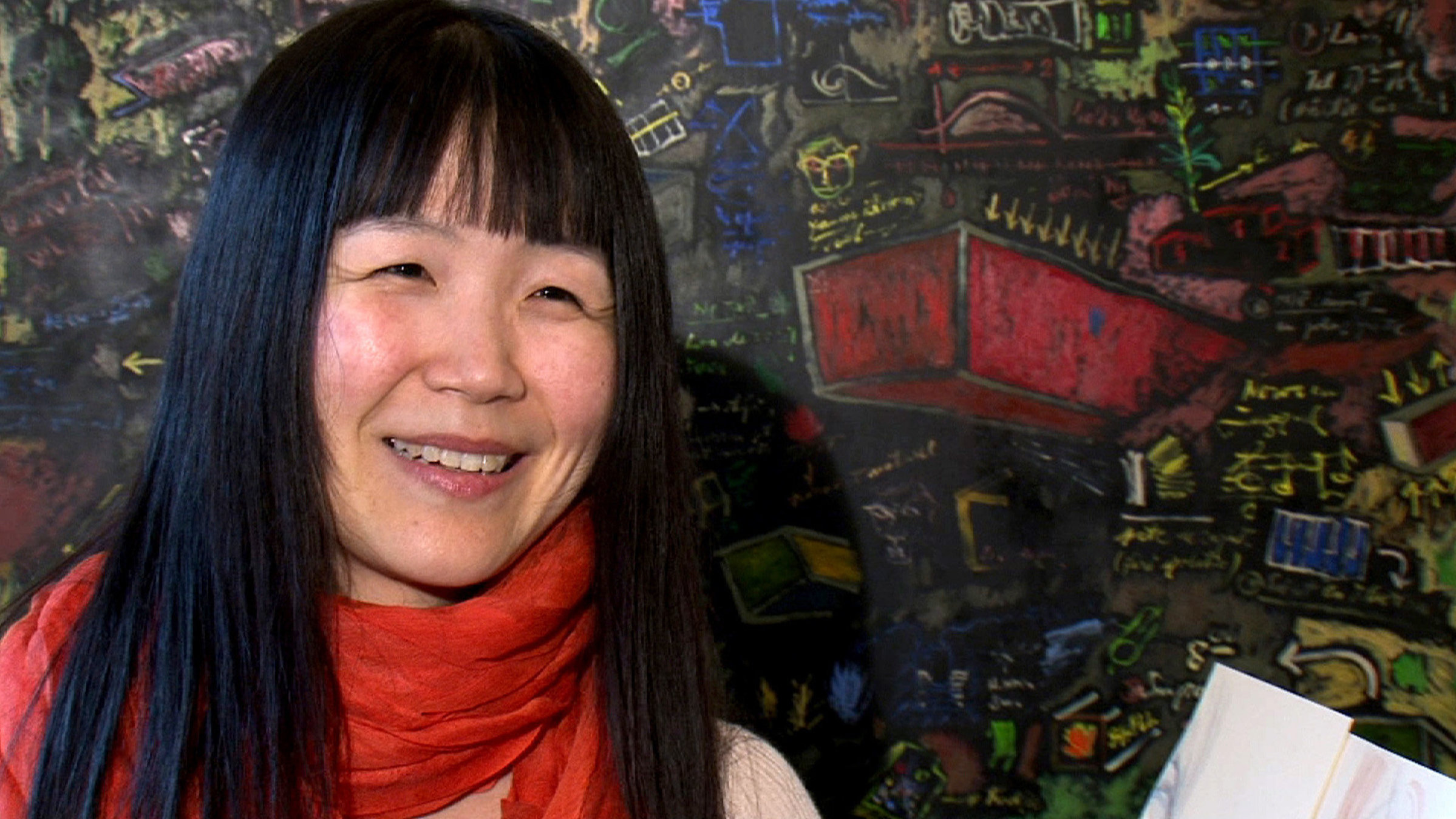 "Leben mit vermischten Sinnen": Die Pianistin Nobuko Akiyama vor einem modernen bunten Gemälde.